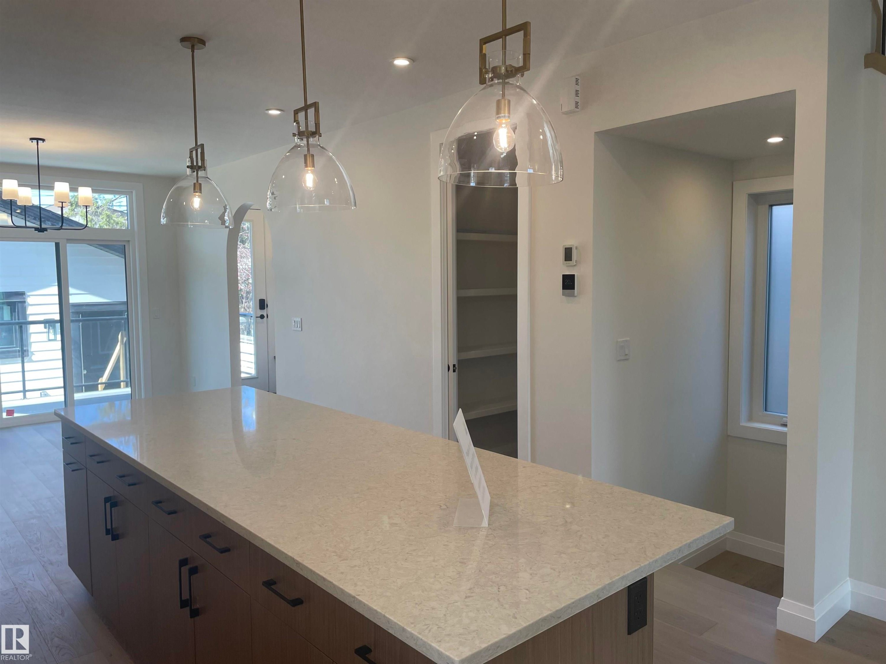 Spacious kitchen island featuring a light-colored countertop and integrated wood-finish cabinetry with dark hardware - 14344 92A Avenue, Edmonton, AB - Indoor Photo Showing Kitchen