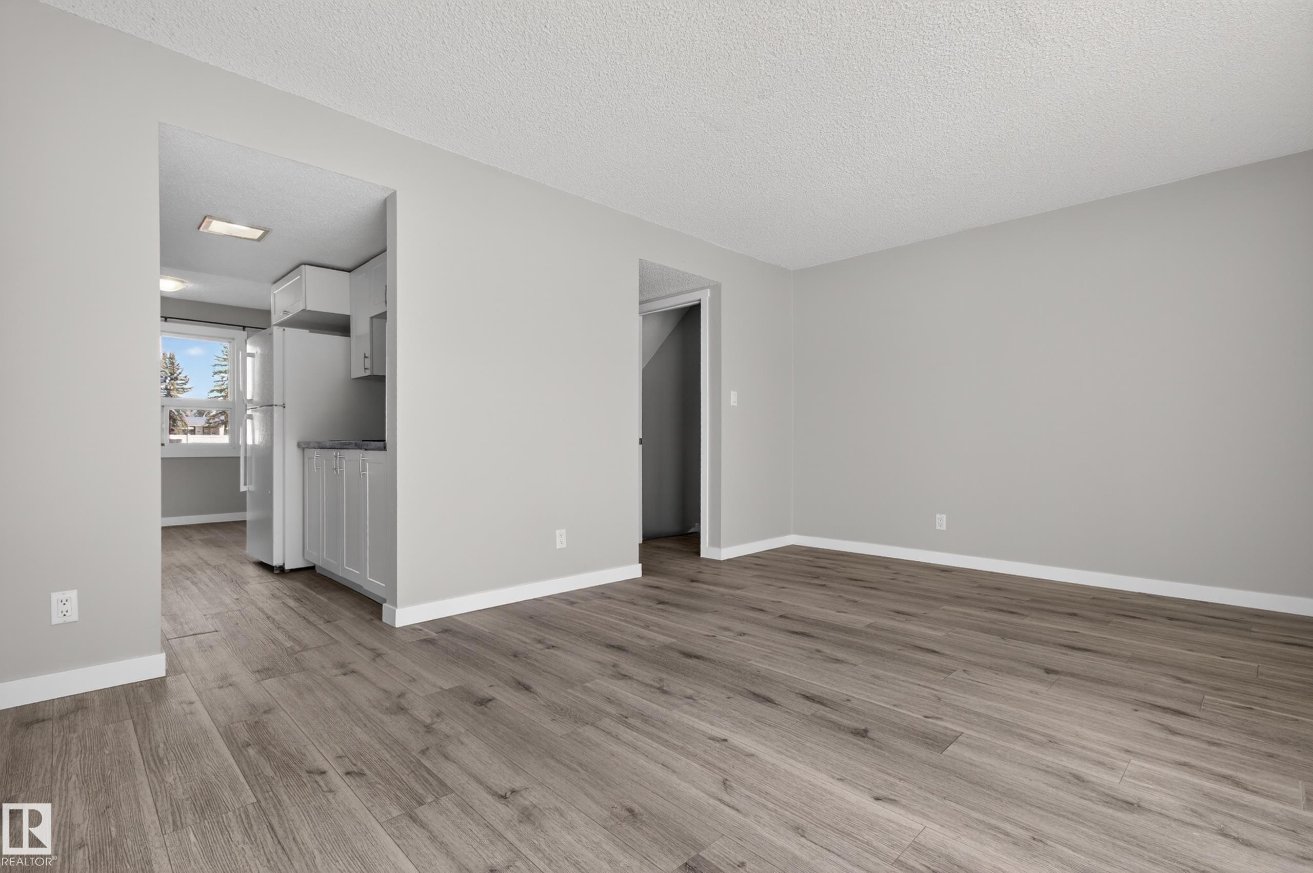 Living area featuring wood-finish flooring, light gray wall paint, and white baseboards - 18 Lakewood Village, Edmonton, AB - Indoor Photo Showing Other Room