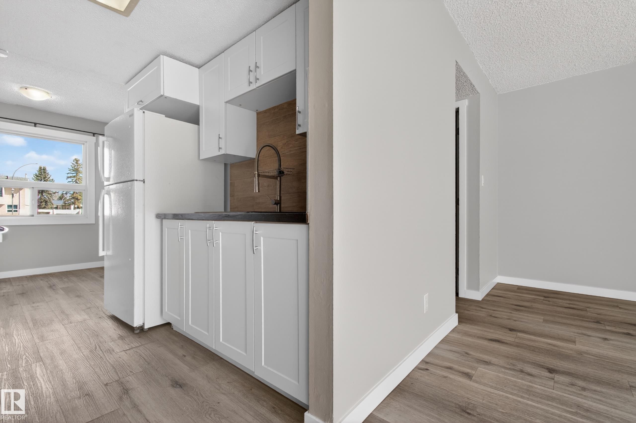 Kitchenette area featuring white cabinetry, a dark countertop, and a dark-toned backsplash - 18 Lakewood Village, Edmonton, AB - Indoor Photo Showing Kitchen