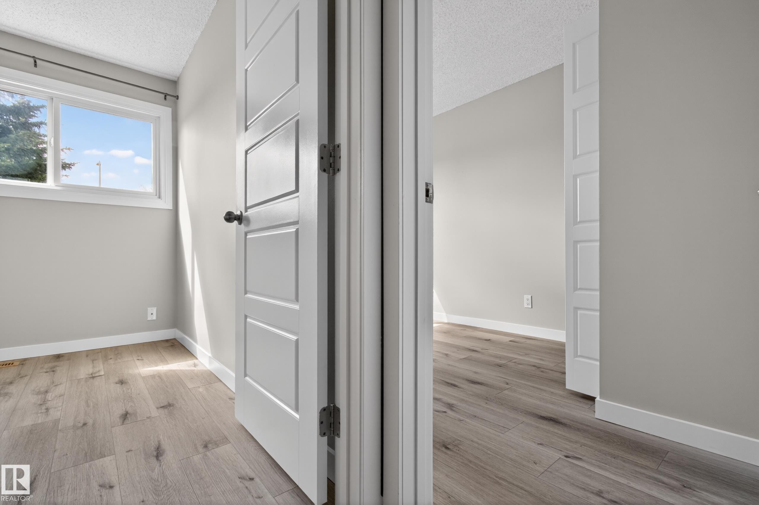 Interior room with wood-finish flooring, light grey painted walls, and white baseboards - 18 Lakewood Village, Edmonton, AB - Indoor Photo Showing Other Room