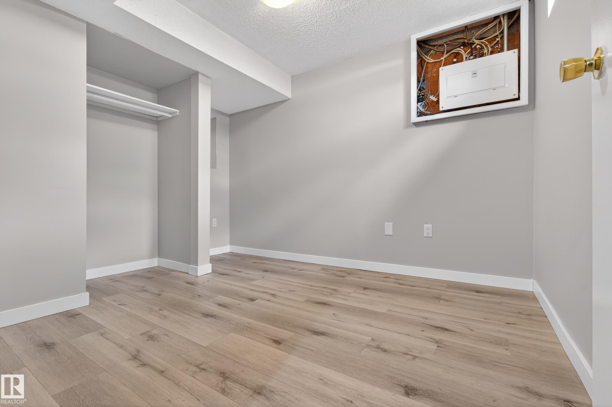 Spacious room featuring wood-finish flooring, light gray wall paint, white baseboards, and a built-in closet area with shelving - 18 Lakewood Village, Edmonton, AB - Indoor Photo Showing Other Room