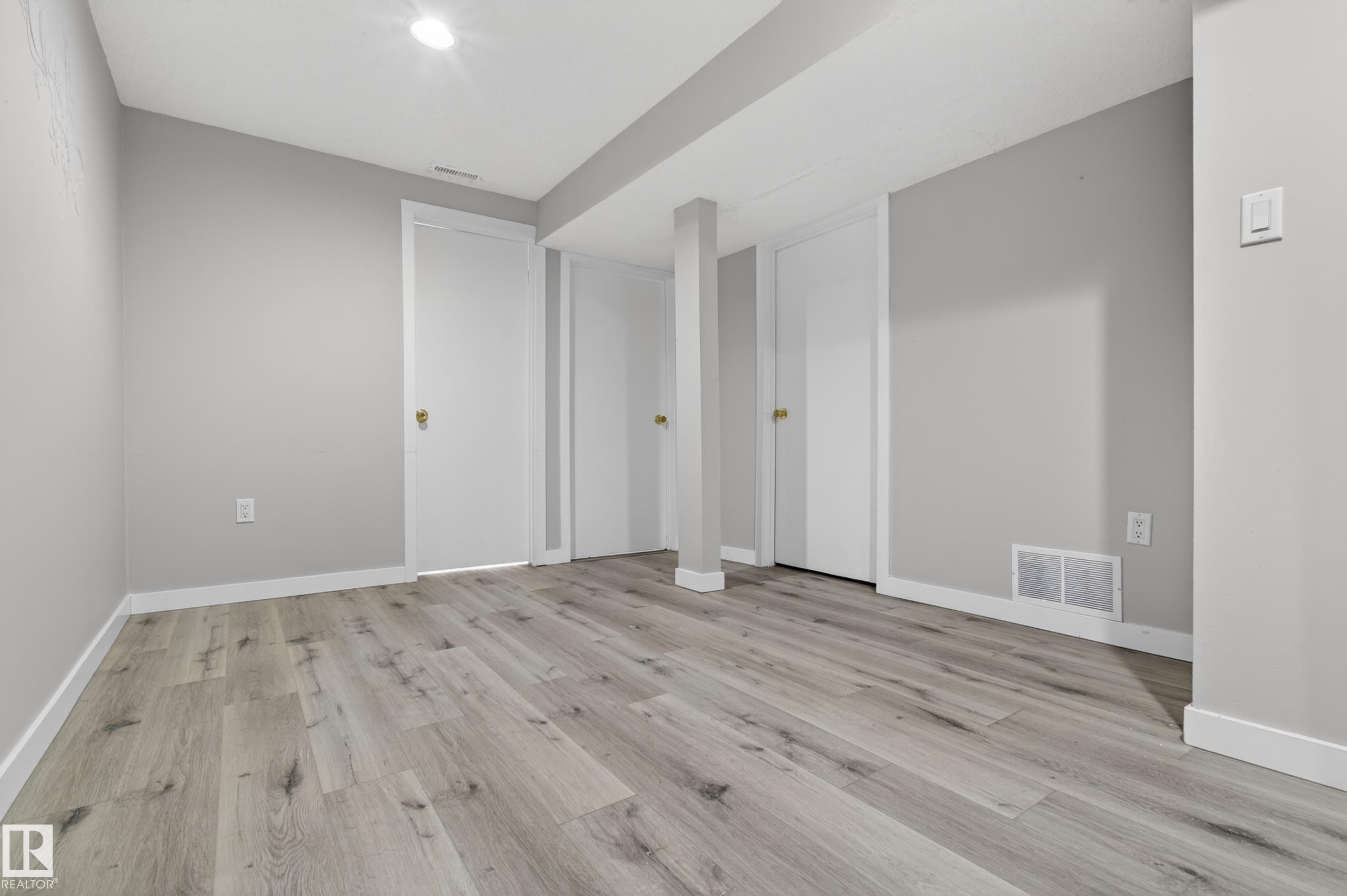 Spacious interior featuring wide plank wood-finish flooring, light gray wall paint, crisp white baseboards, and recessed ceiling lighting - 18 Lakewood Village, Edmonton, AB - Indoor Photo Showing Other Room