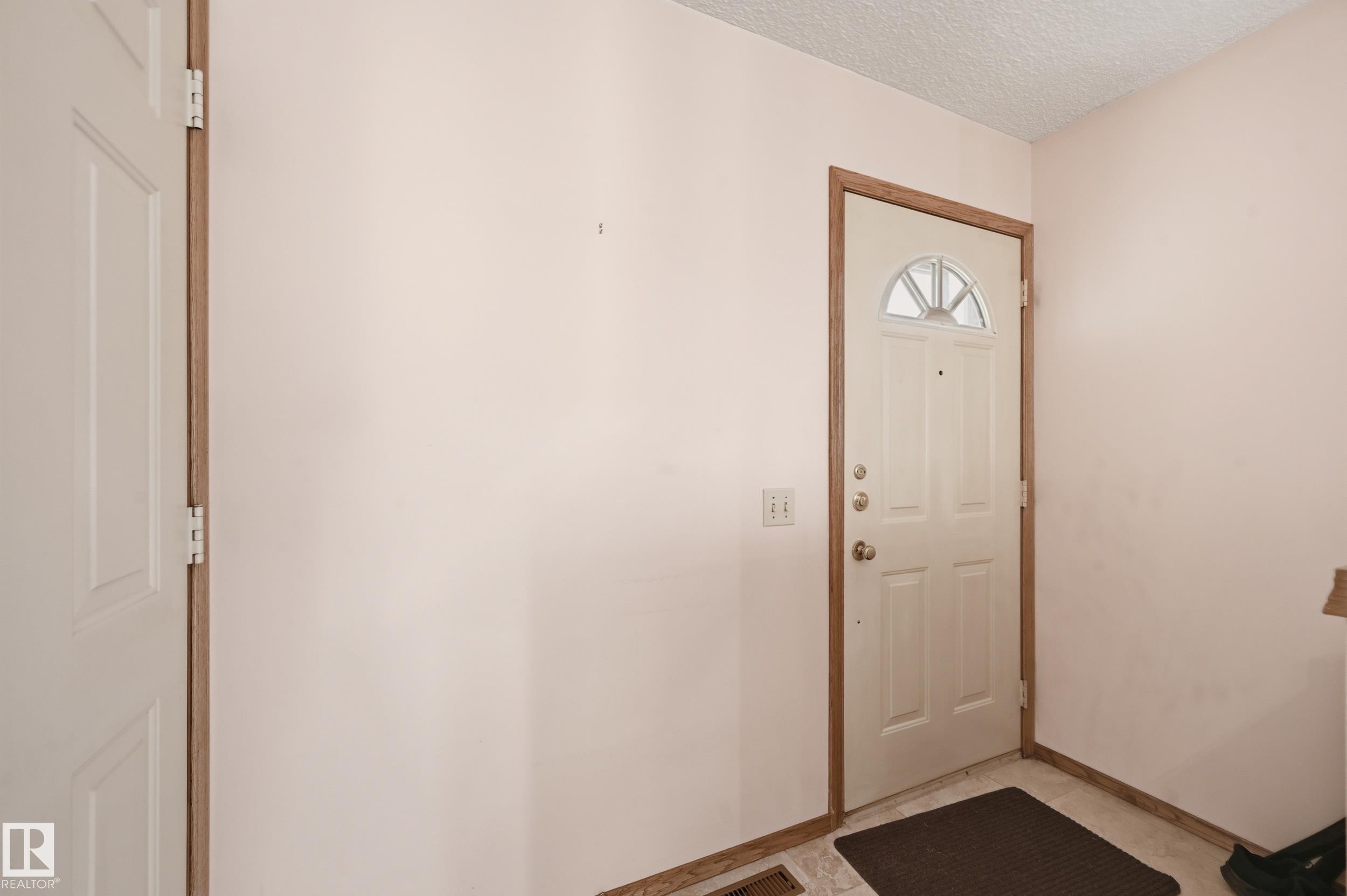 Entryway featuring a paneled door with an arched window, wood-finish trim, and light-toned wall finishes - 1242 Joyce Crescent, Edmonton, AB - Indoor Photo Showing Other Room