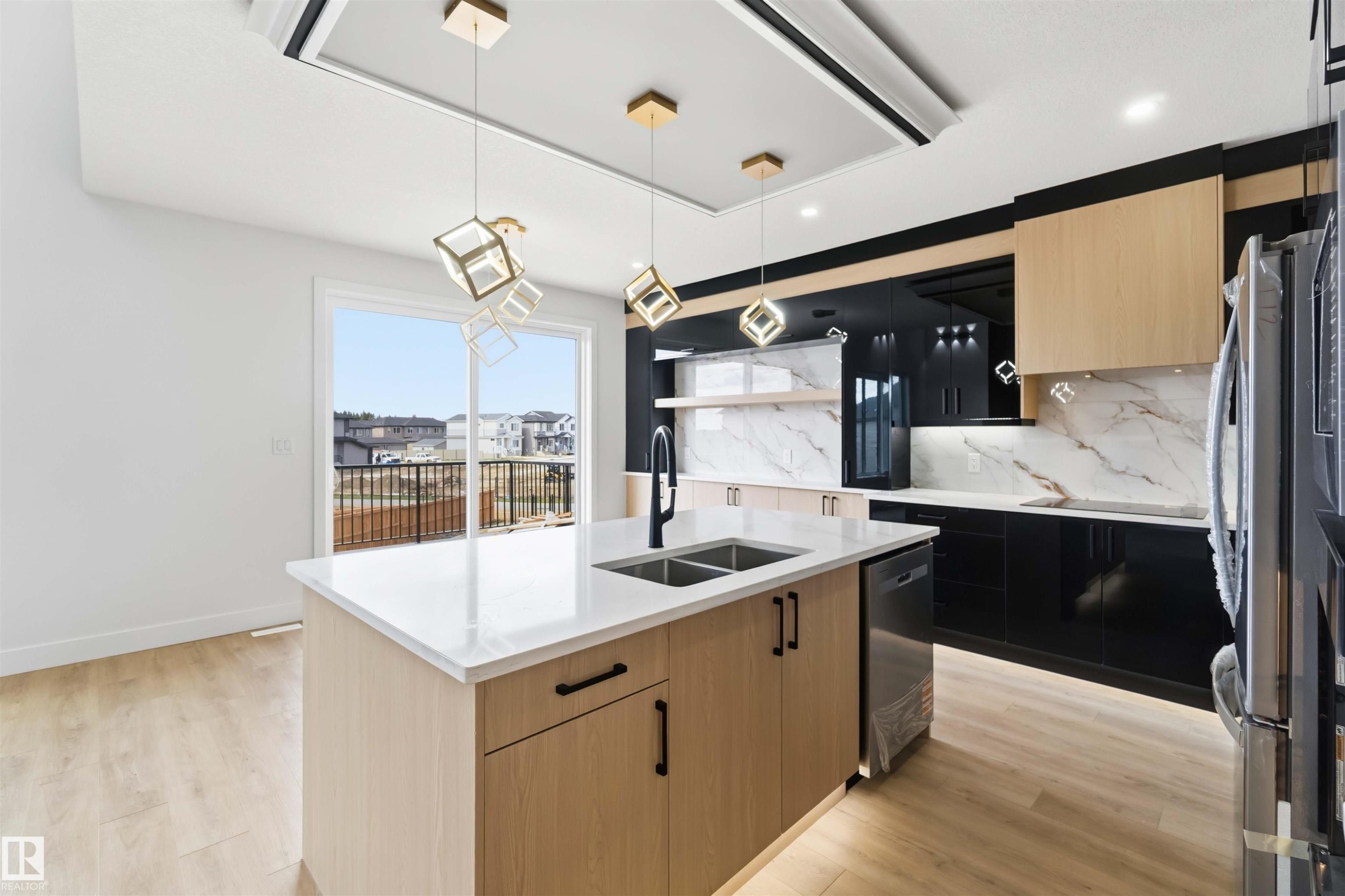 Modern kitchen featuring a central island with an undermount sink, white countertops, black high-gloss cabinetry, wood-finish upper cabinetry, and a marble-patterned backsplash - 417 Pine Point(E), Leduc, AB - Indoor Photo Showing Kitchen With Double Sink With Upgraded Kitchen