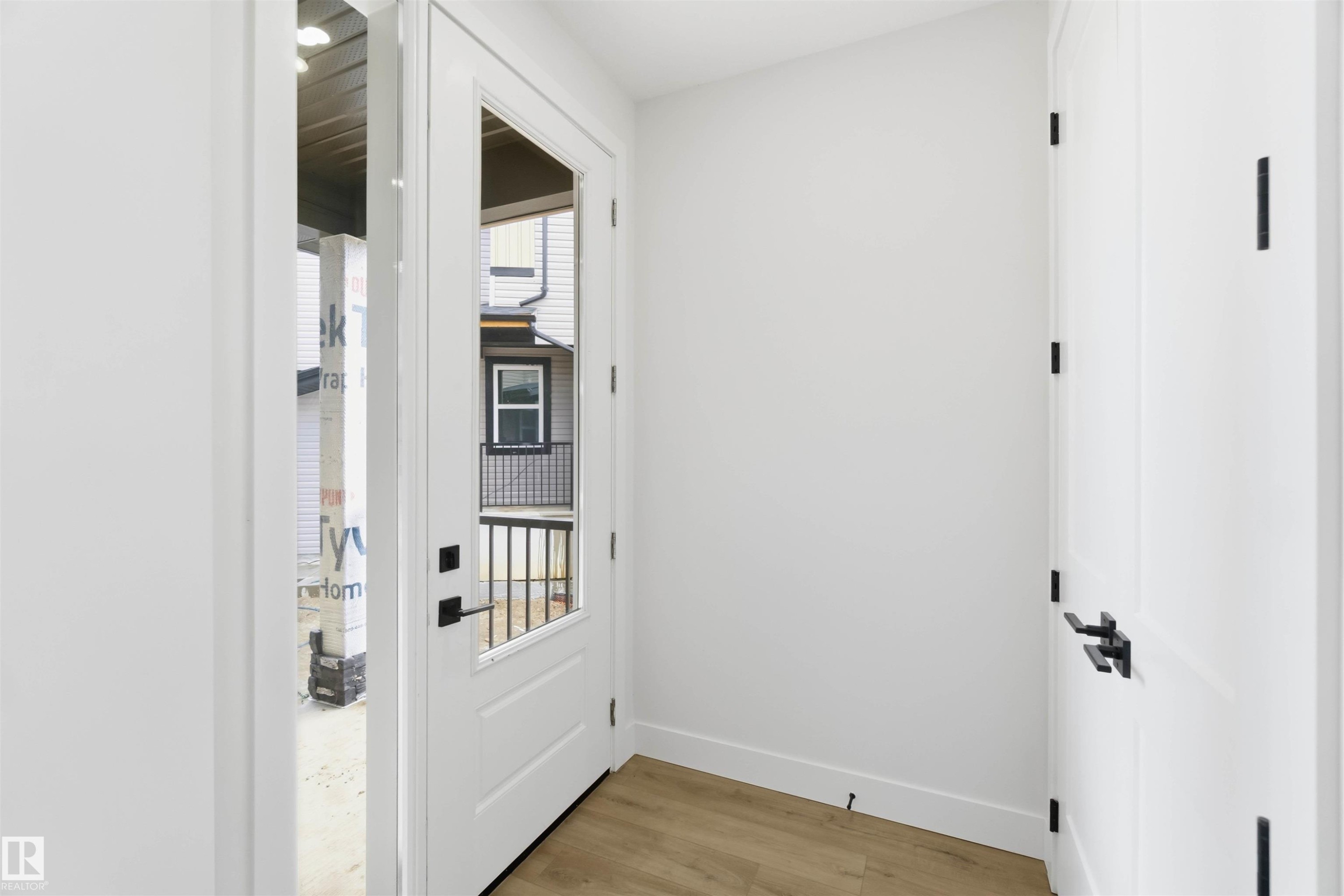 Entryway featuring a white door with a clear glass insert, matte black hardware, and wood-finish flooring - 417 Pine Point(E), Leduc, AB - Indoor Photo Showing Other Room