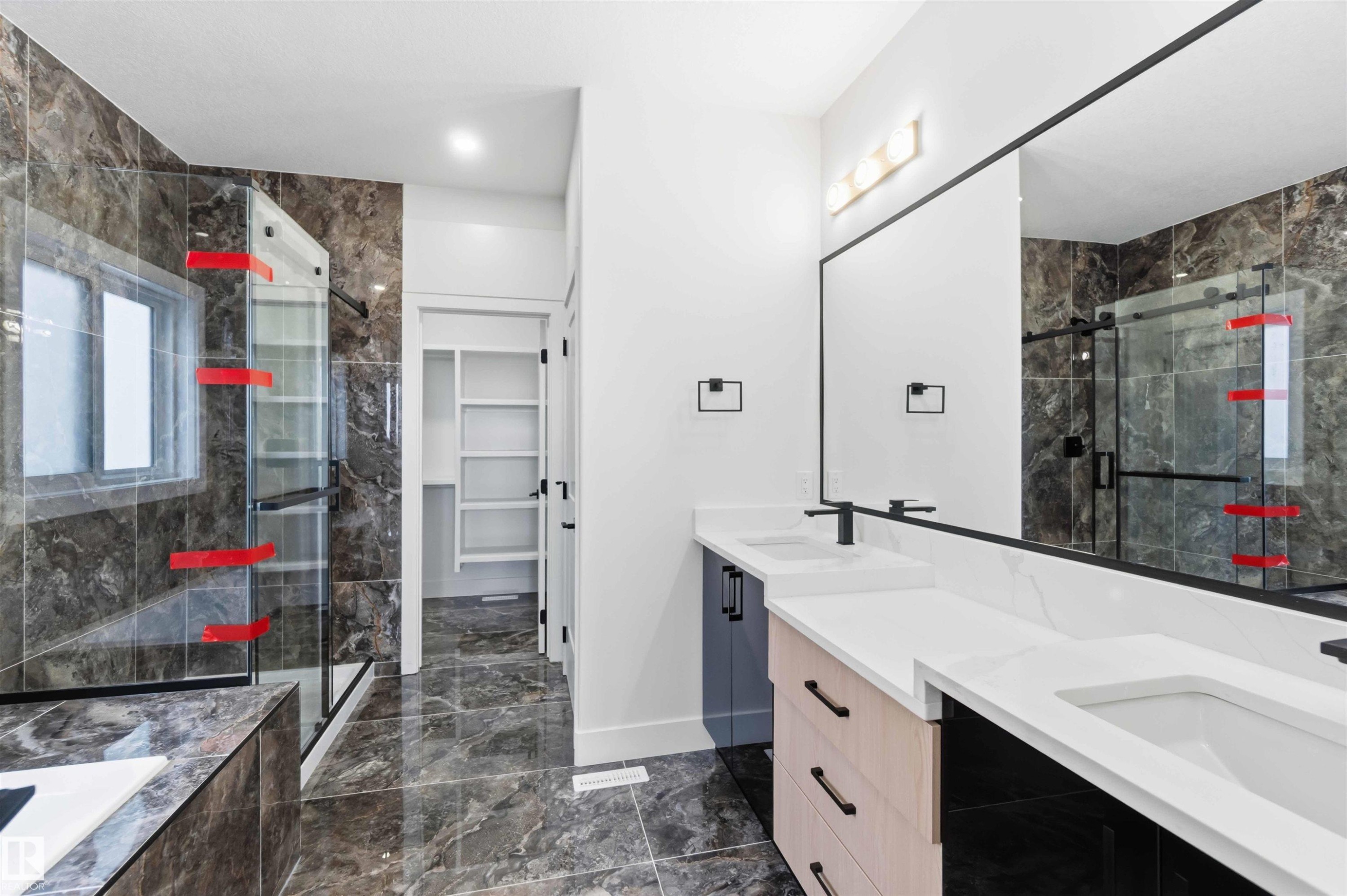 Modern bathroom featuring a dual vanity with white countertops, matte black hardware, and a large frameless mirror - 417 Pine Point(E), Leduc, AB - Indoor Photo Showing Bathroom