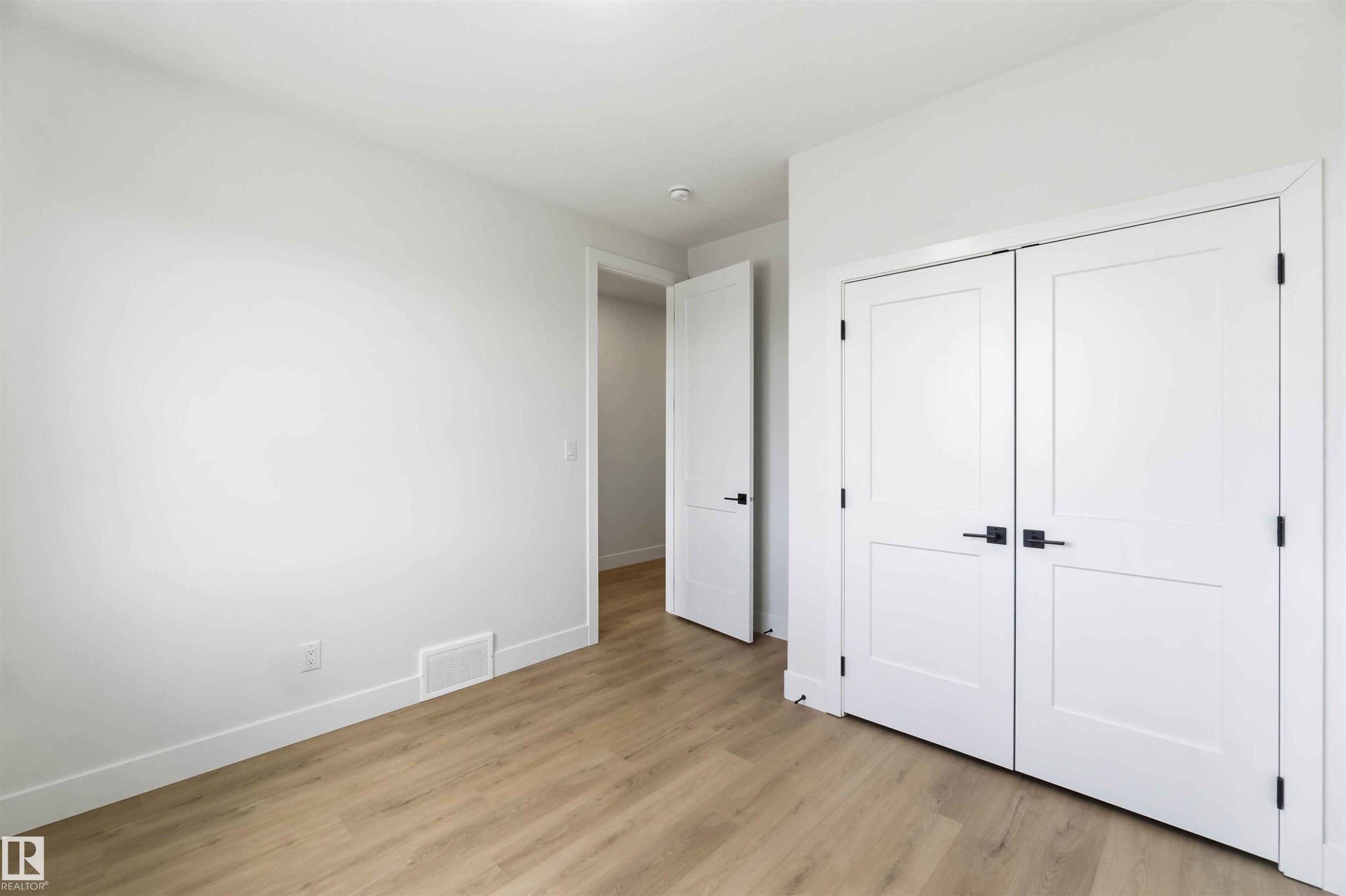 Light wood-finish flooring complements white walls and trim - 417 Pine Point(E), Leduc, AB - Indoor Photo Showing Other Room