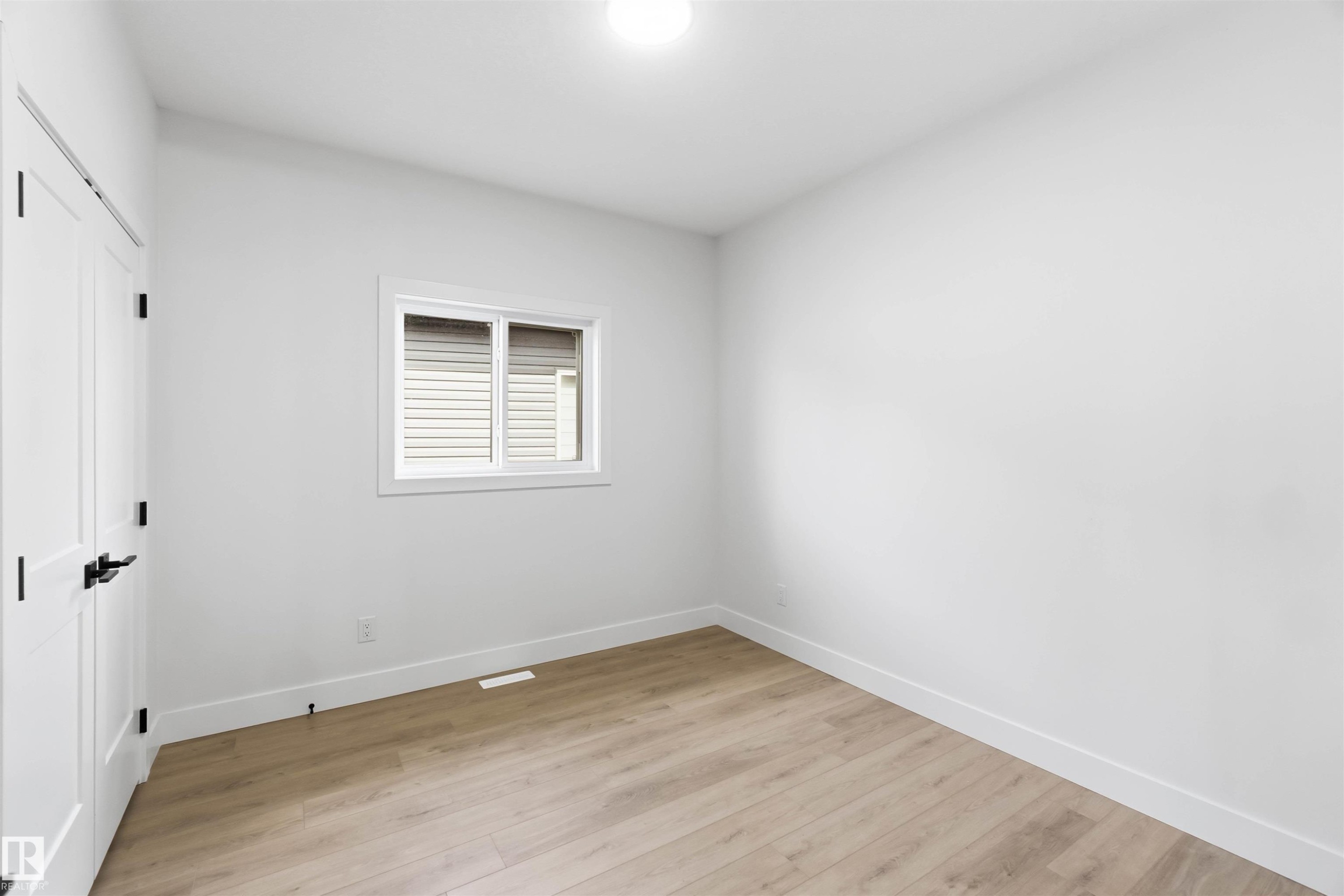 Room featuring wood-finish flooring, crisp white walls, and a white-framed window - 417 Pine Point(E), Leduc, AB - Indoor Photo Showing Other Room