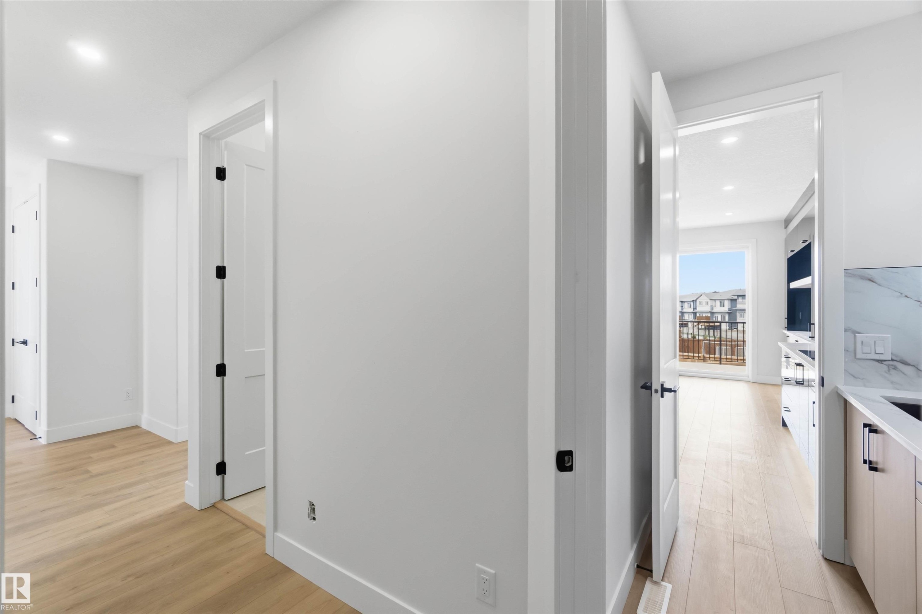 Hallway featuring wood-finish flooring, recessed lighting, white trim, and matte black door hardware - 417 Pine Point(E), Leduc, AB - Indoor