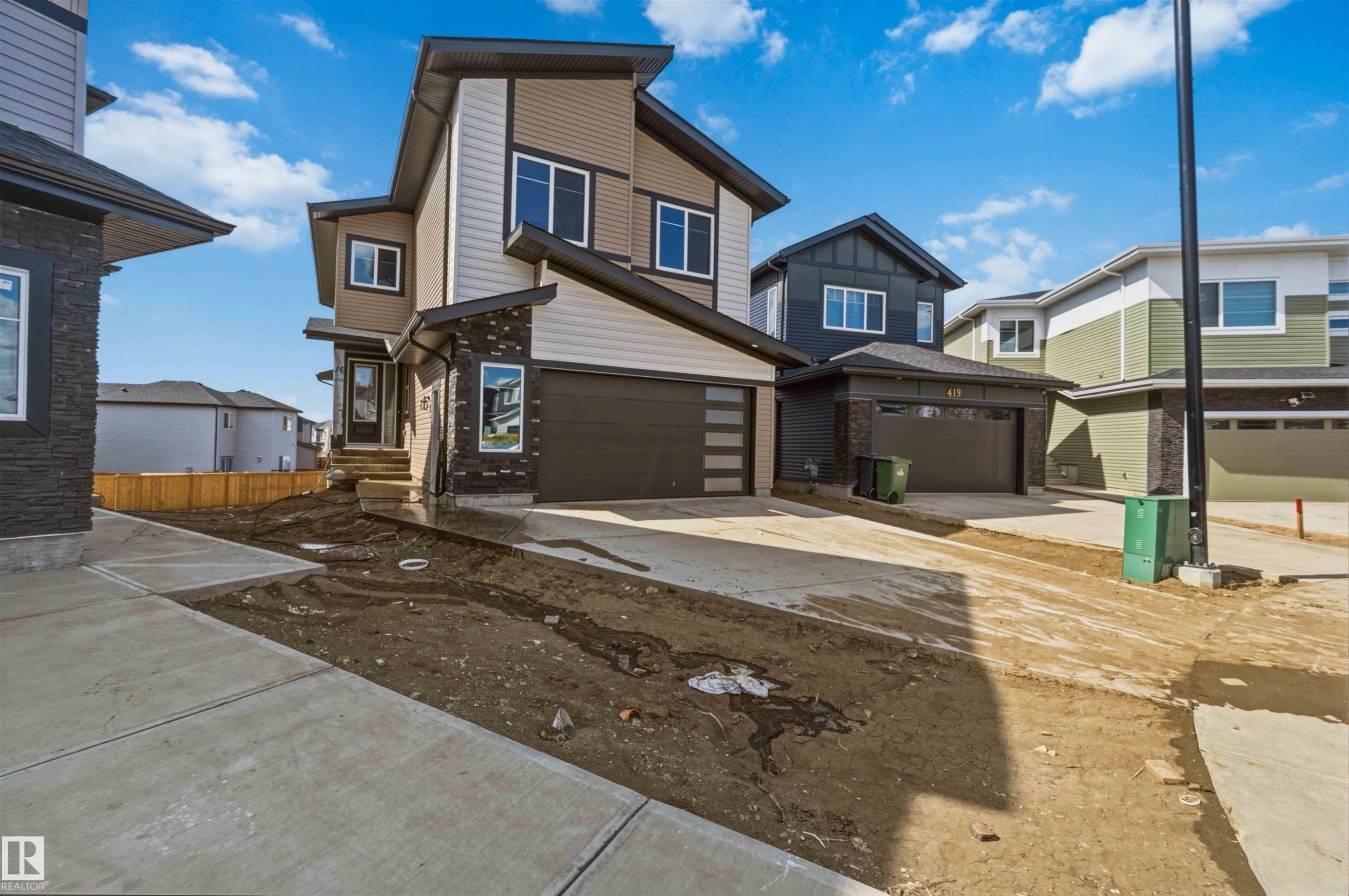 Contemporary two-story exterior featuring multiple cladding materials, dark-framed windows, an integrated garage with a modern door, and a concrete driveway - 417 Pine Point(E), Leduc, AB - Outdoor