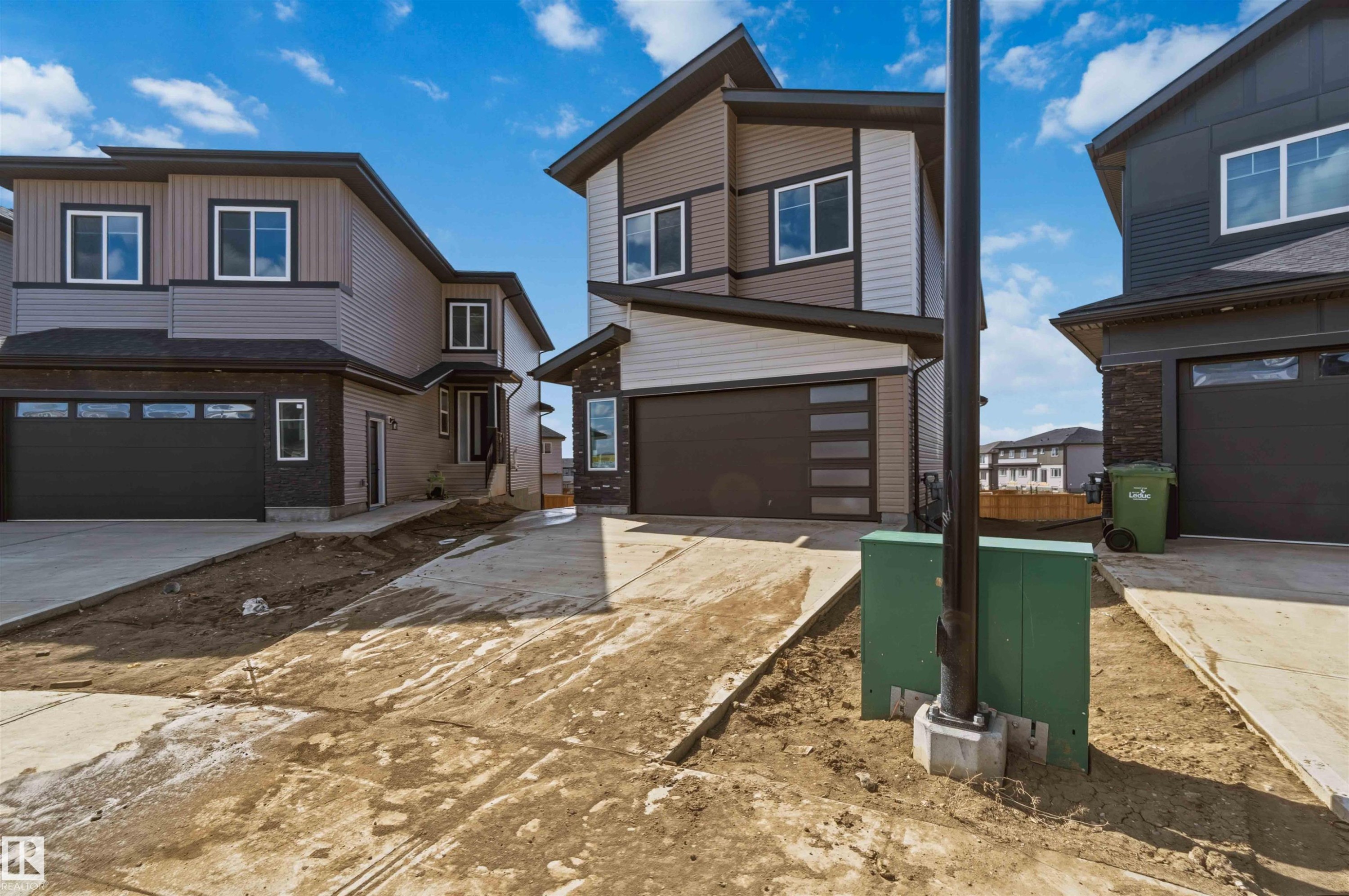 Contemporary two-story exterior featuring a multi-tone facade with dark siding, light siding, and stone accents - 417 Pine Point(E), Leduc, AB - Outdoor