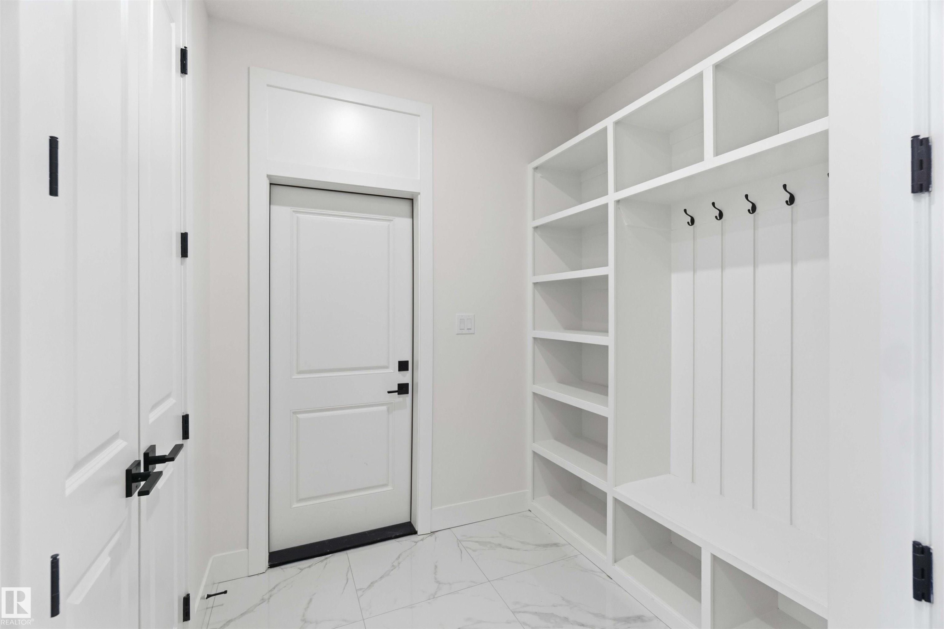 Entryway featuring built-in white shelving, integrated bench seating, and black coat hooks - 415 Pine Point(E), Leduc, AB - Indoor