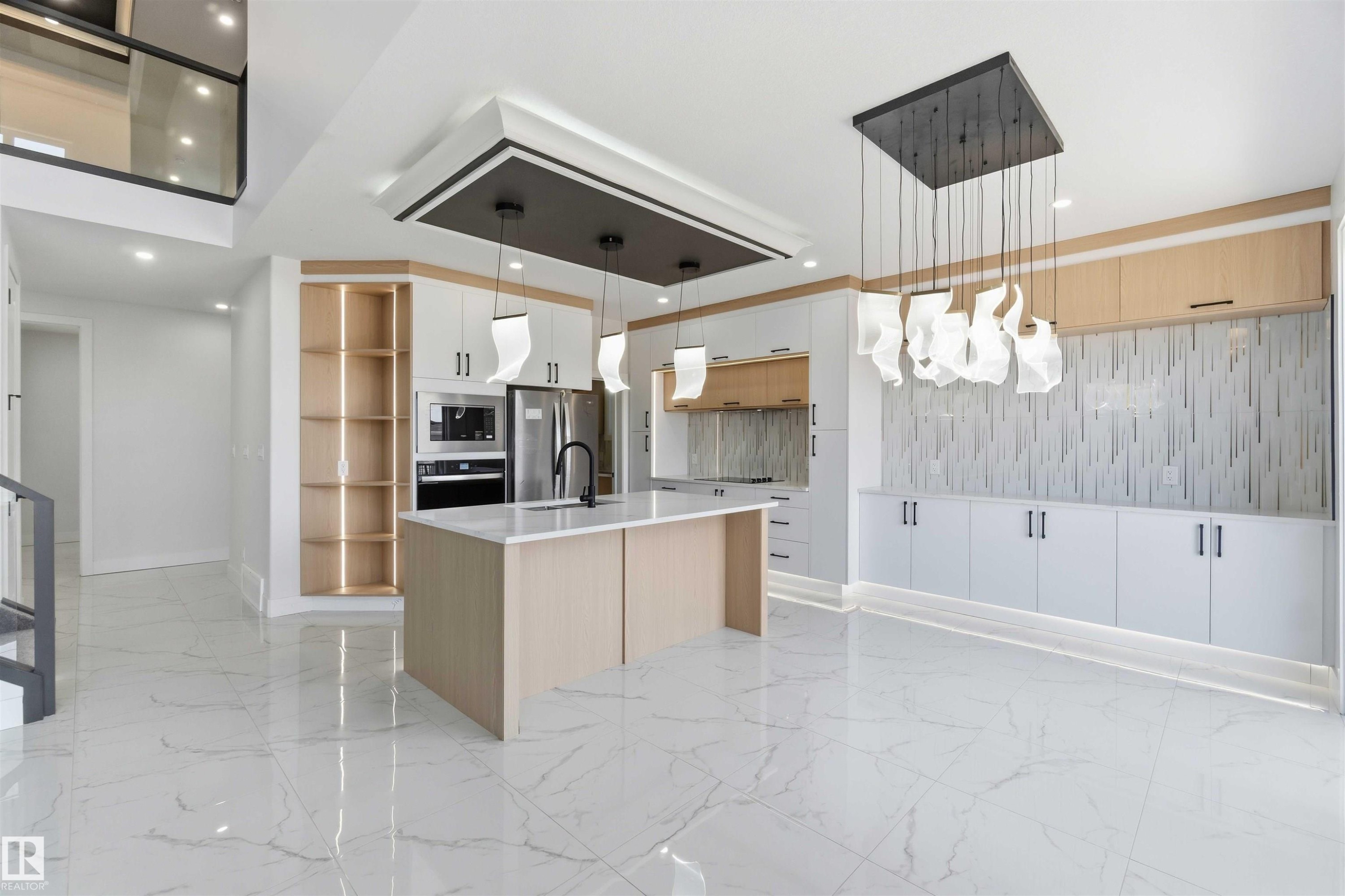 Spacious kitchen featuring an expansive island with a quartz countertop, integrated stainless steel appliances, and custom cabinetry - 415 Pine Point(E), Leduc, AB - Indoor Photo Showing Kitchen