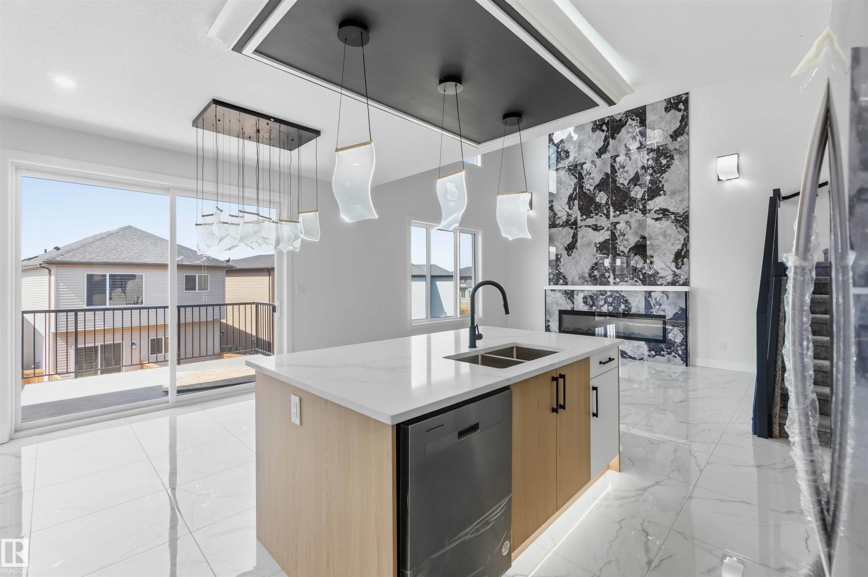 Modern kitchen island featuring a waterfall countertop, integrated sink with matte black faucet, and built-in dishwasher - 415 Pine Point(E), Leduc, AB - Indoor Photo Showing Kitchen With Double Sink With Upgraded Kitchen