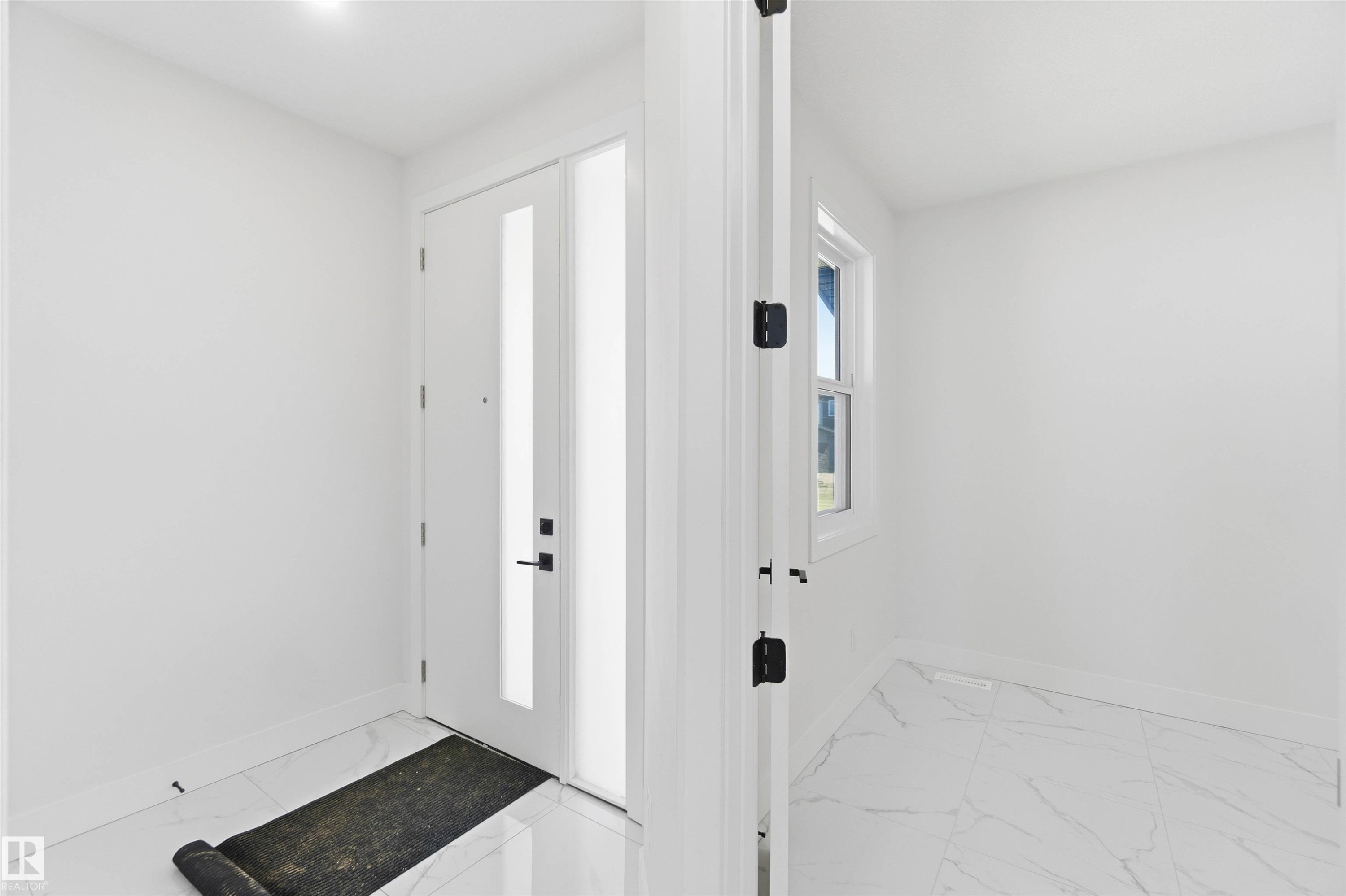 Entryway featuring a white door with vertical frosted glass panels, matte black hardware, and a coordinating frosted glass sidelight - 415 Pine Point(E), Leduc, AB - Indoor Photo Showing Other Room