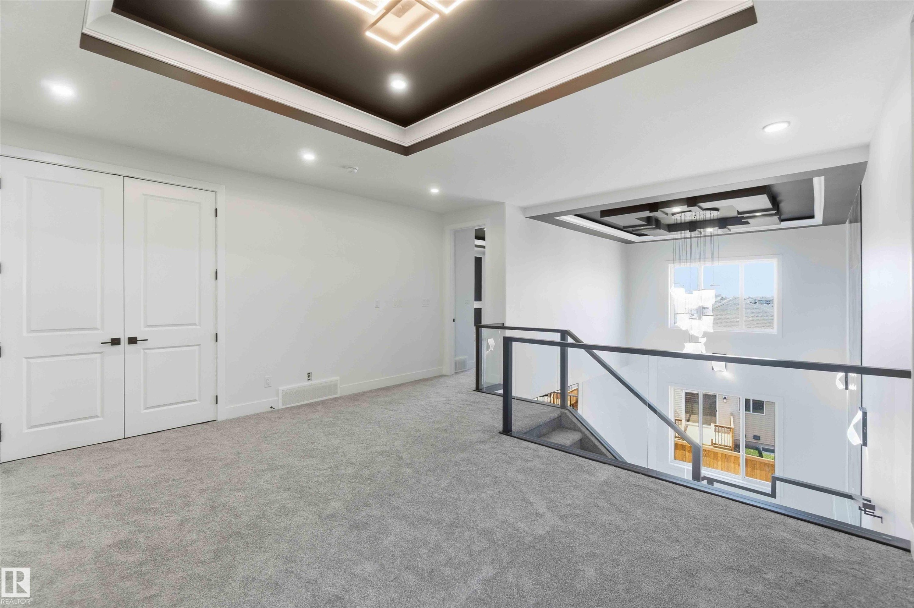 Open landing area featuring gray carpeting, modern glass and metal railing, and recessed ceiling lighting - 415 Pine Point(E), Leduc, AB - Indoor Photo Showing Other Room