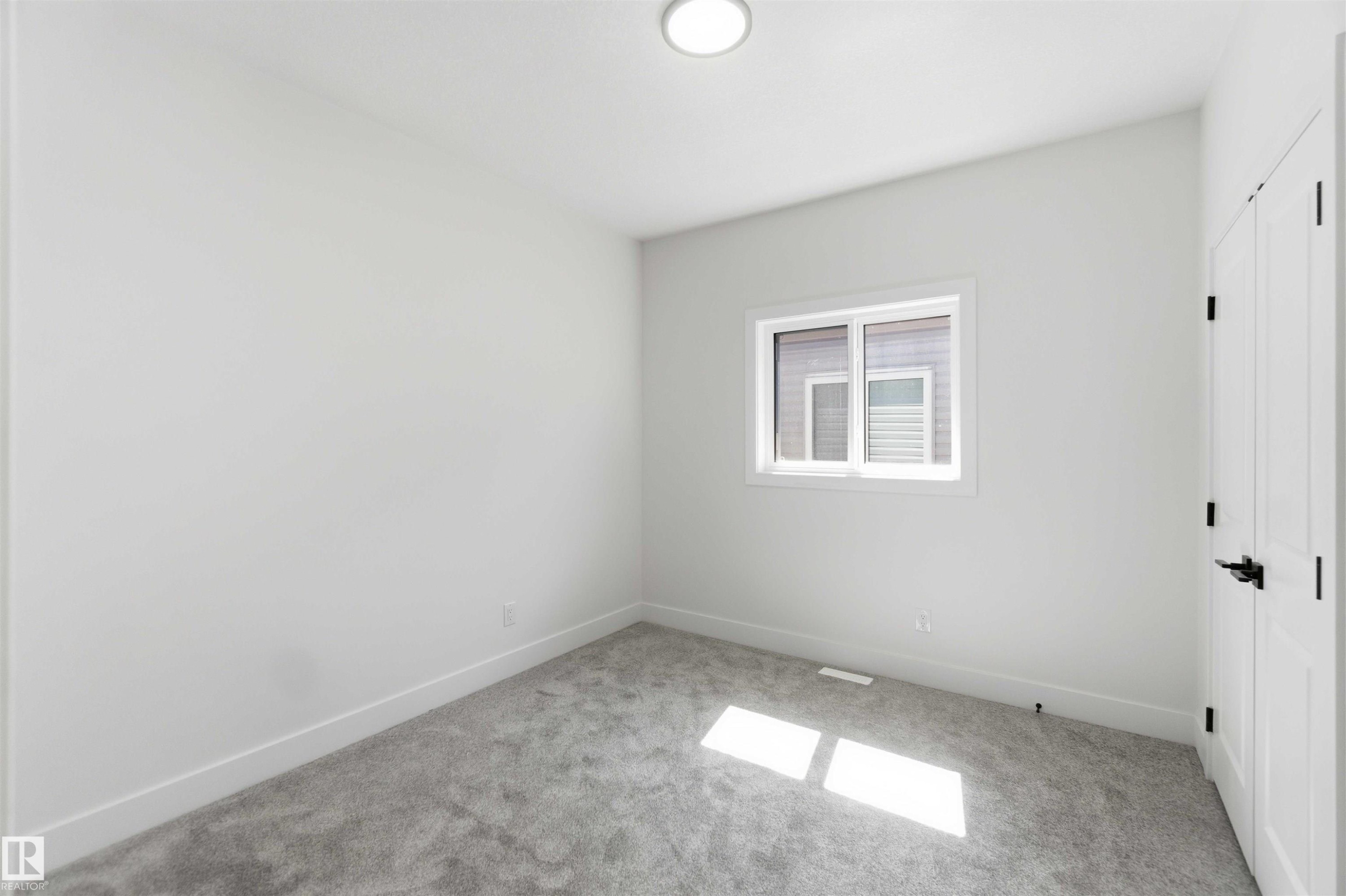 Bright room featuring a window with white trim, gray carpet, white walls, and a flush mount ceiling light - 415 Pine Point(E), Leduc, AB - Indoor Photo Showing Other Room