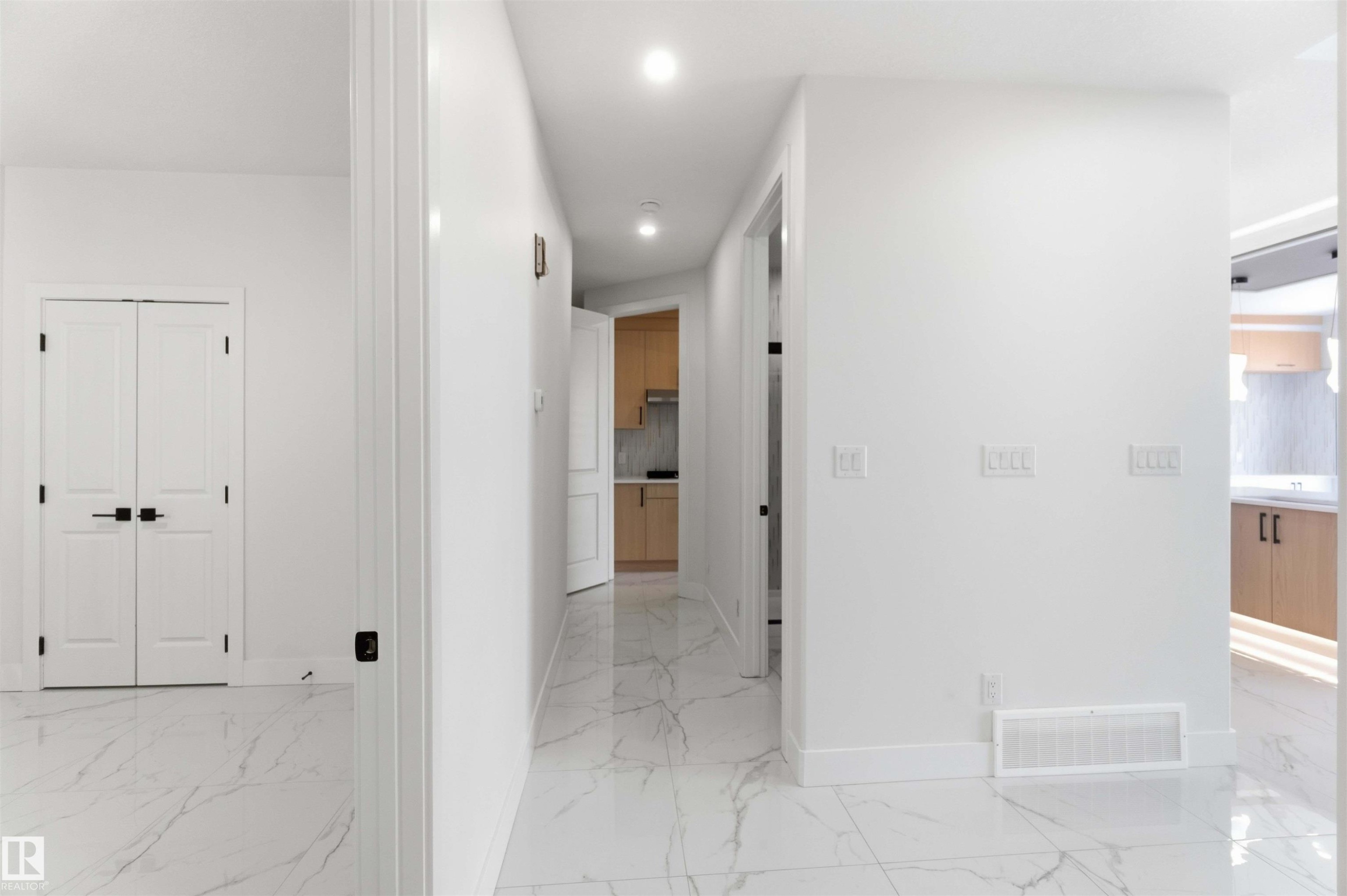 Spacious interior hallway featuring white walls, recessed lighting, and large format marble-look tile flooring - 415 Pine Point(E), Leduc, AB - Indoor Photo Showing Other Room