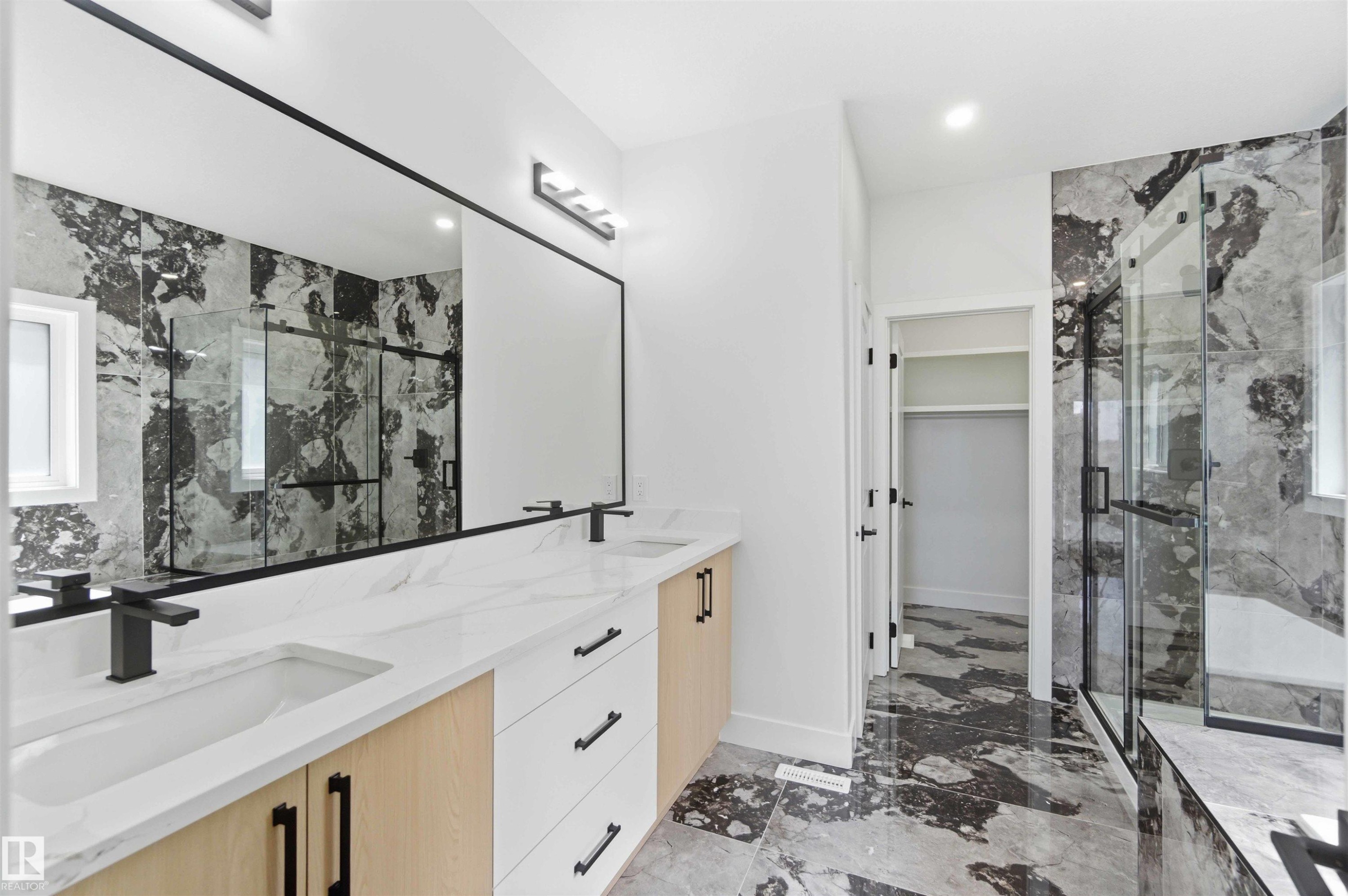 Modern bathroom featuring a dual vanity with white countertops, light wood-finish cabinetry, and matte black fixtures - 415 Pine Point(E), Leduc, AB - Indoor Photo Showing Bathroom