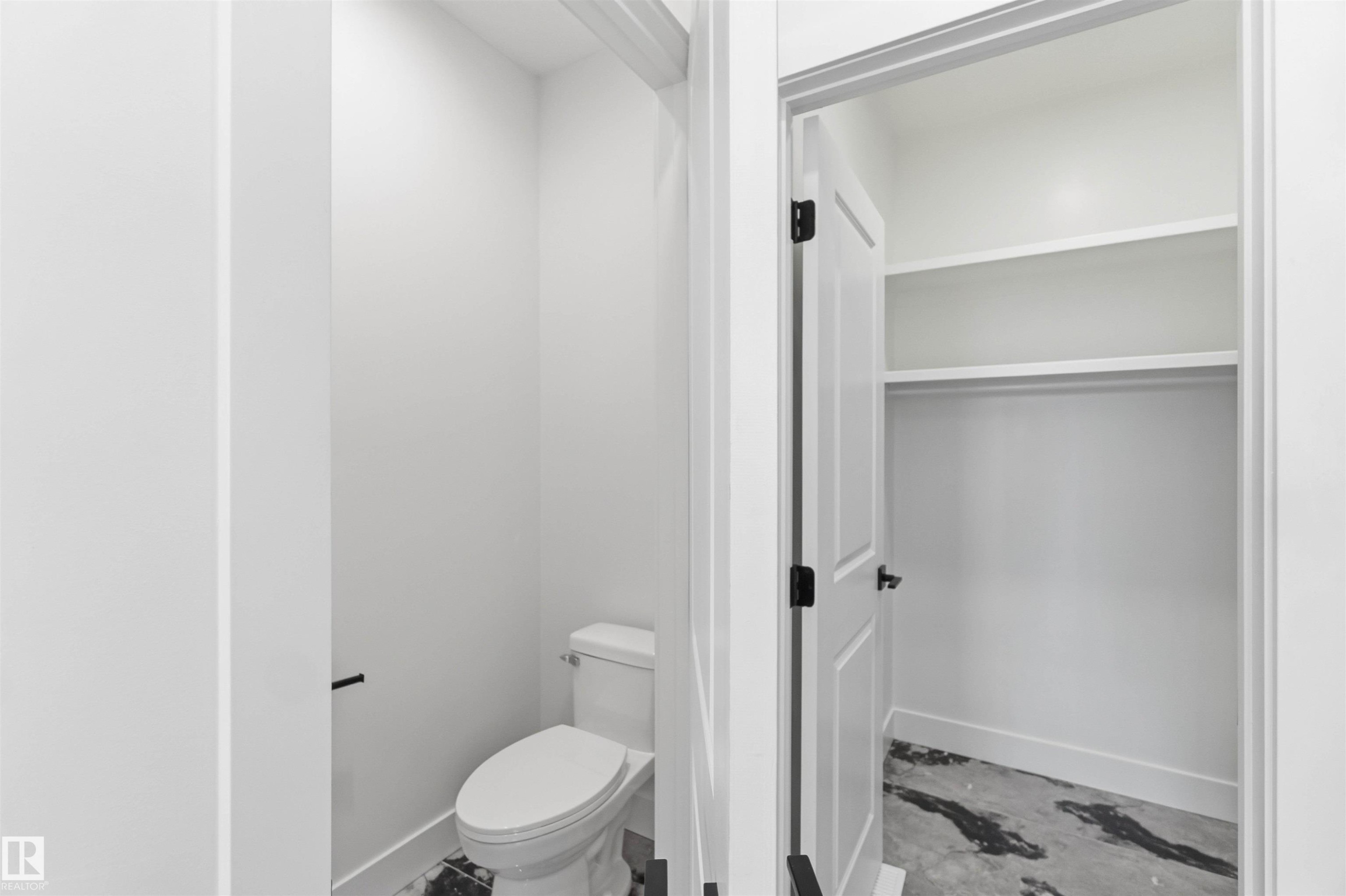 Powder room featuring a white toilet with black floor tiling - 415 Pine Point(E), Leduc, AB - Indoor Photo Showing Bathroom