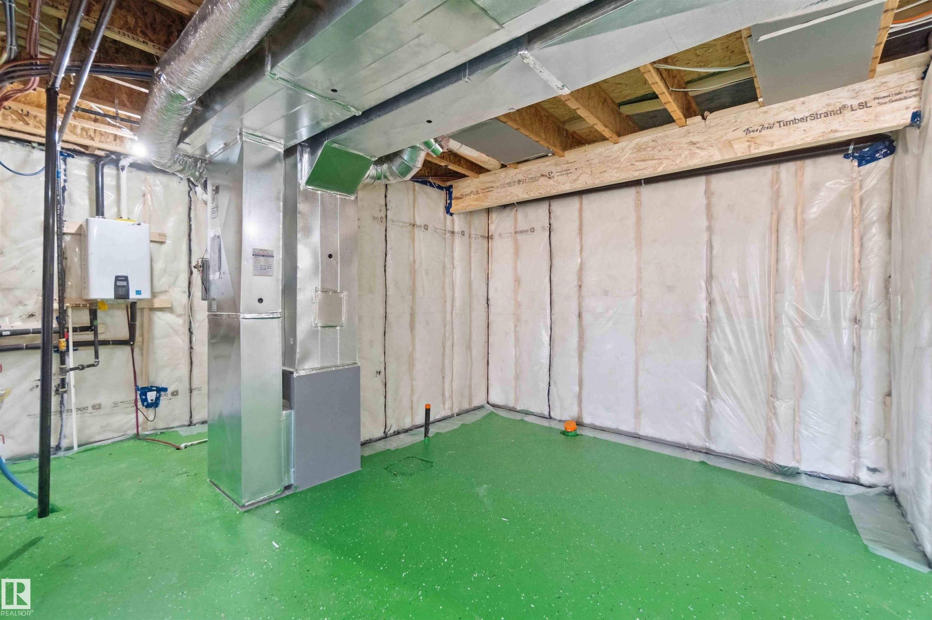 Unfinished basement space featuring a bright green epoxy floor coating, exposed ceiling joists, and insulated walls - 415 Pine Point(E), Leduc, AB - Indoor Photo Showing Basement