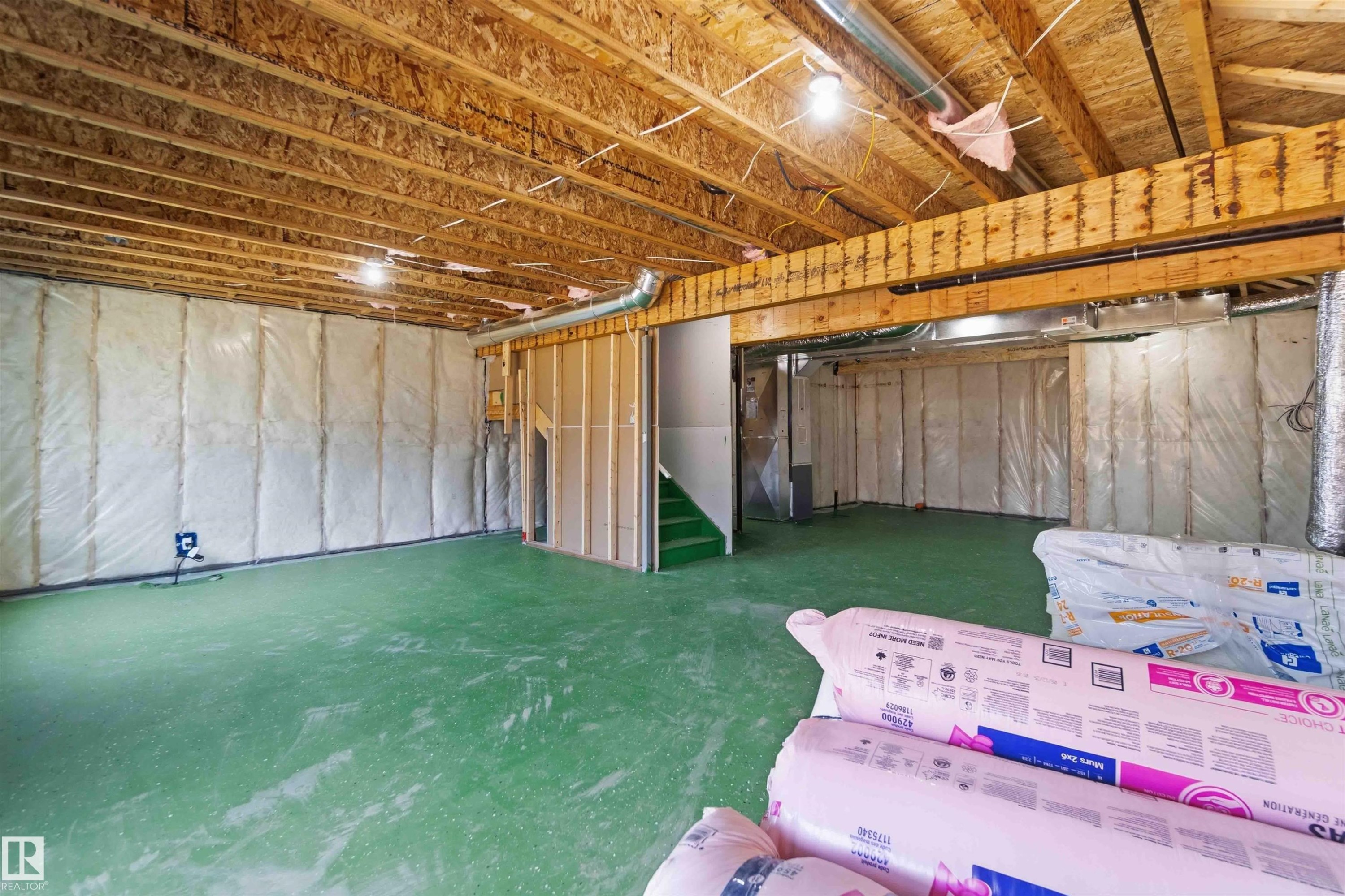 Unfinished basement featuring exposed wood joists and subflooring, insulated perimeter walls, and a green painted concrete floor - 415 Pine Point(E), Leduc, AB - Indoor Photo Showing Basement