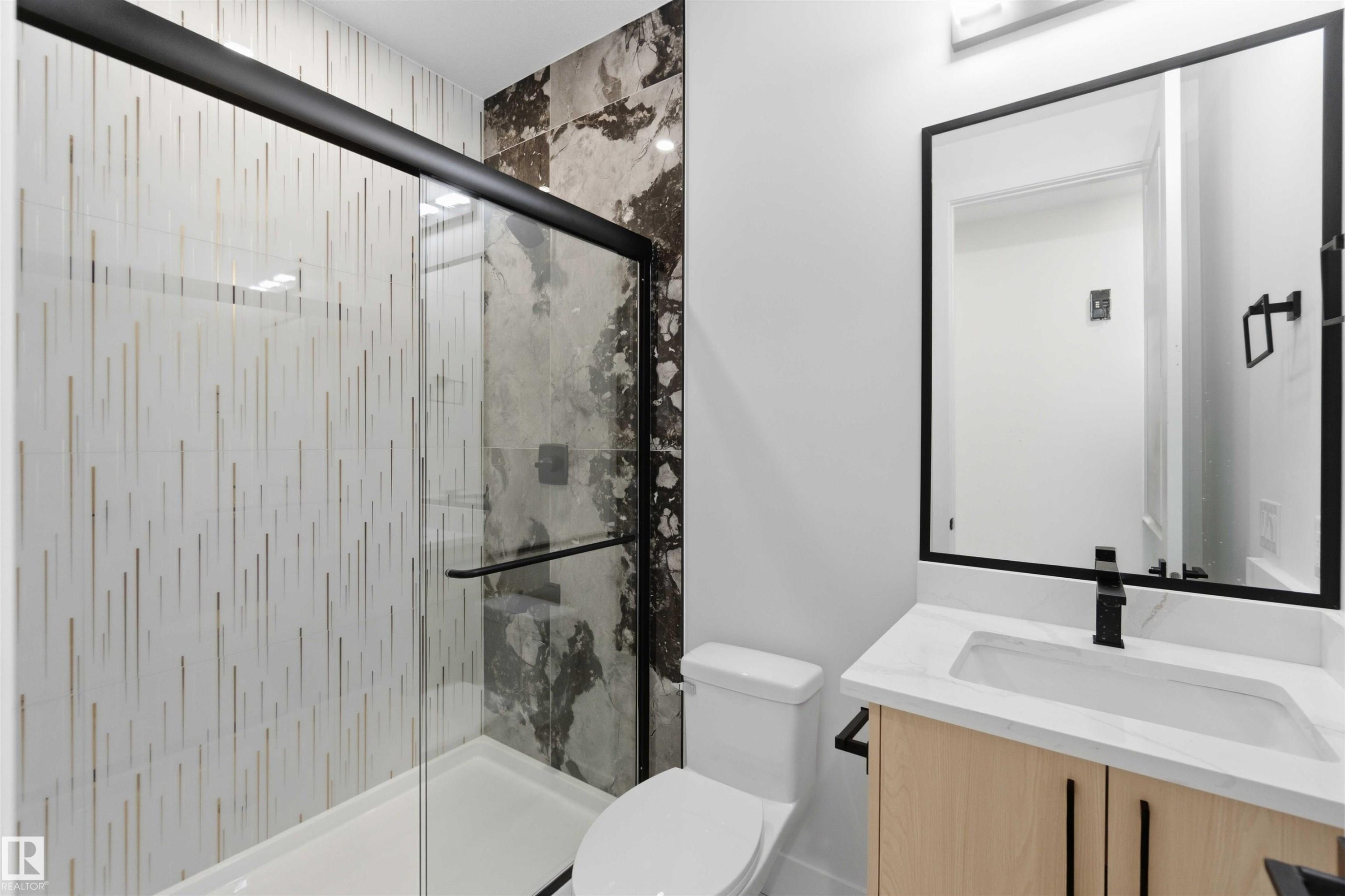 Modern bathroom featuring a glass-enclosed shower with contrasting tile patterns - 415 Pine Point(E), Leduc, AB - Indoor Photo Showing Bathroom