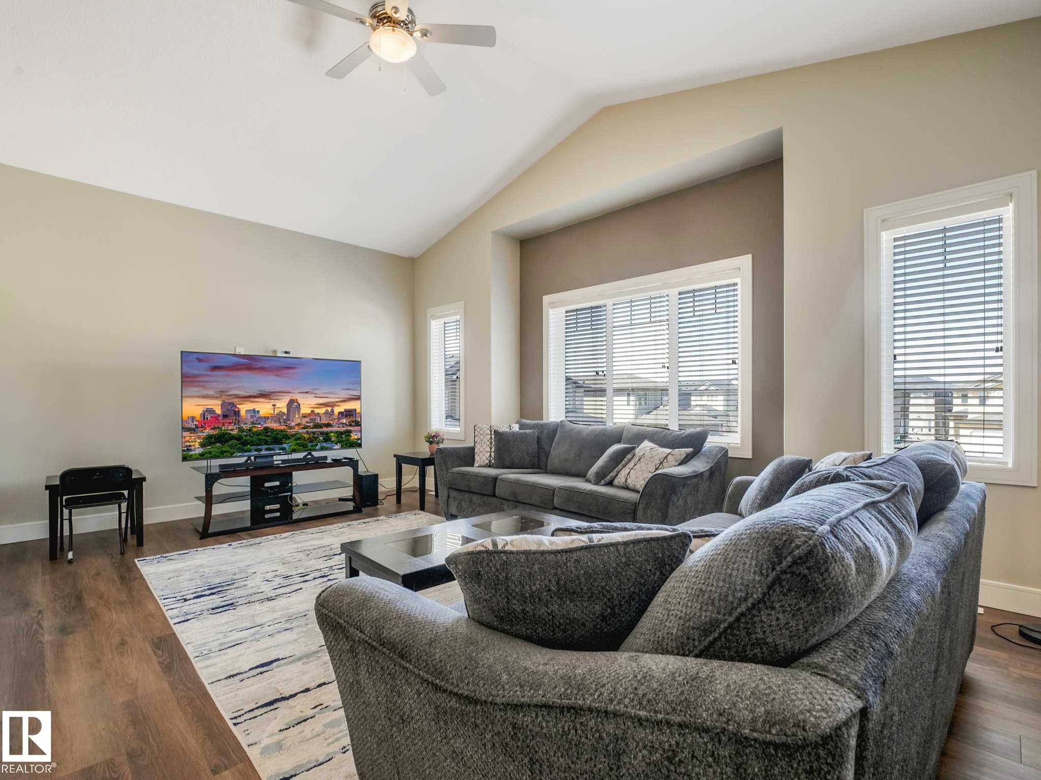Spacious living area featuring vaulted ceilings, wood-finish flooring, and multiple windows with blinds - 16251 135 Street Nw, Edmonton, AB - Indoor Photo Showing Living Room