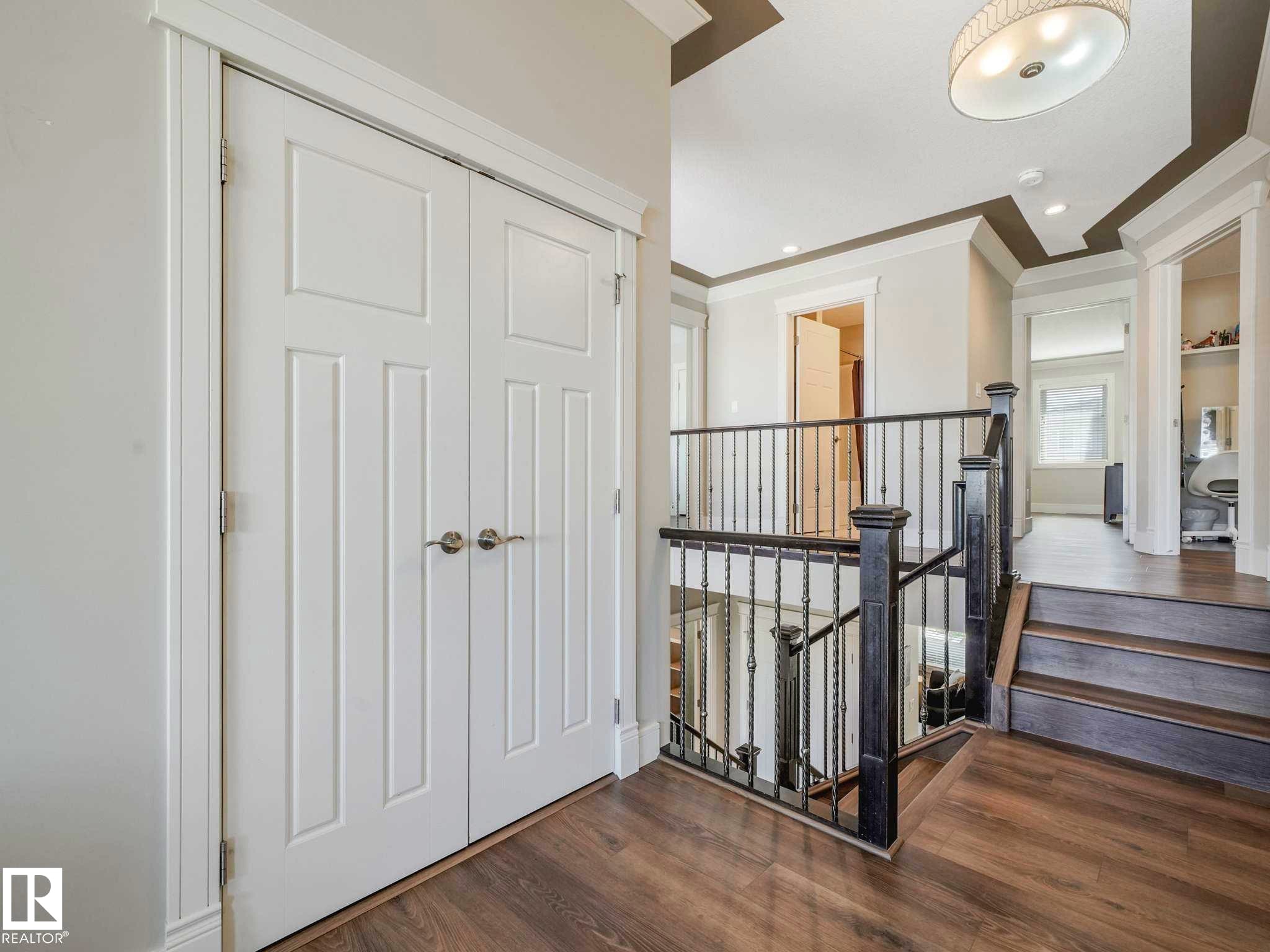 Entryway featuring white bi-fold doors with panel detailing, dark wood-finish flooring, and a decorative ceiling light fixture - 16251 135 Street Nw, Edmonton, AB - Indoor Photo Showing Other Room