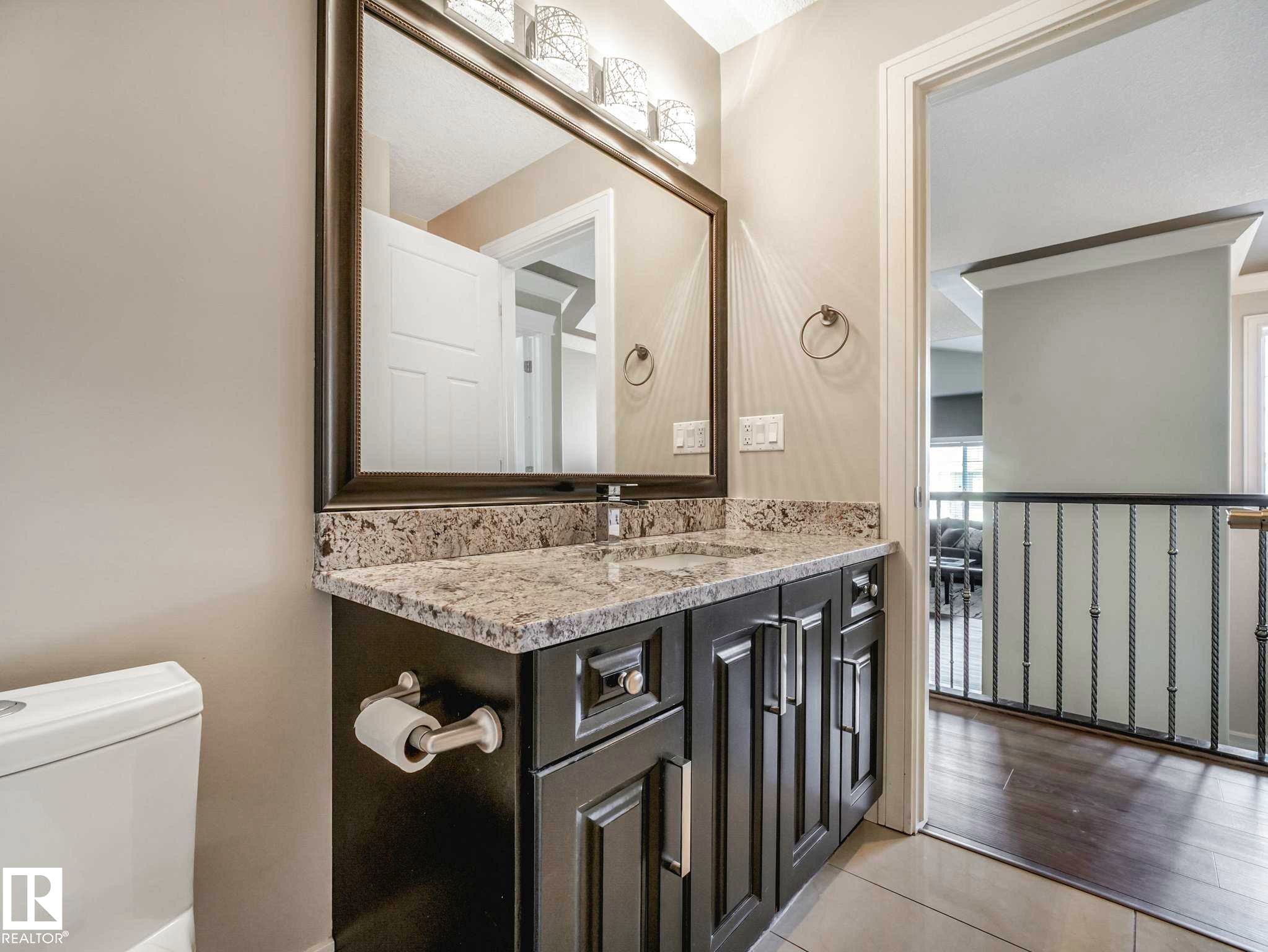 Bathroom vanity with granite-style countertop, undermount sink, and dark wood-finish cabinetry - 16251 135 Street Nw, Edmonton, AB - Indoor Photo Showing Bathroom