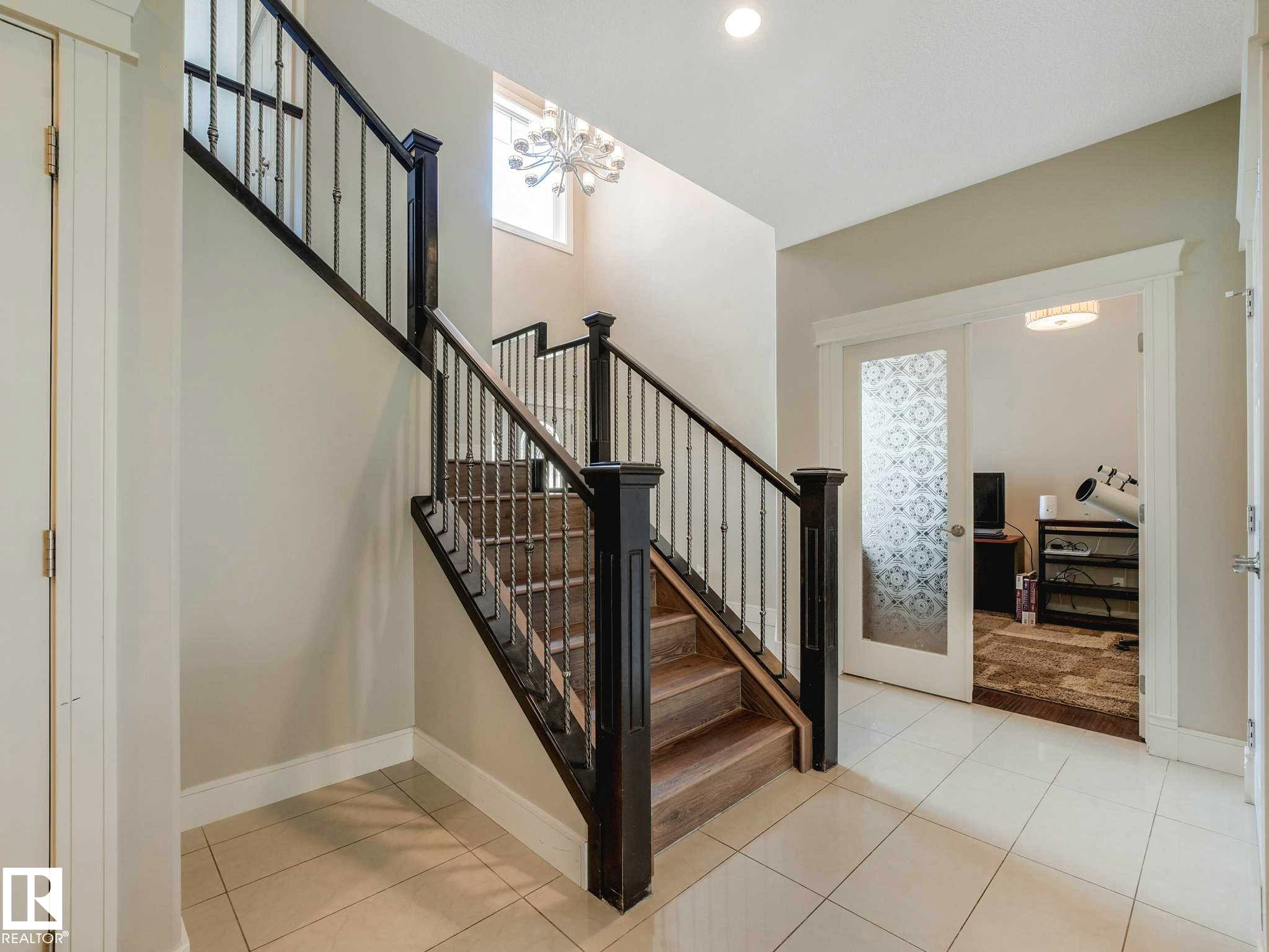 Foyer featuring a grand staircase with dark wood-finish newel posts and wrought iron balusters - 16251 135 Street Nw, Edmonton, AB - Indoor Photo Showing Other Room