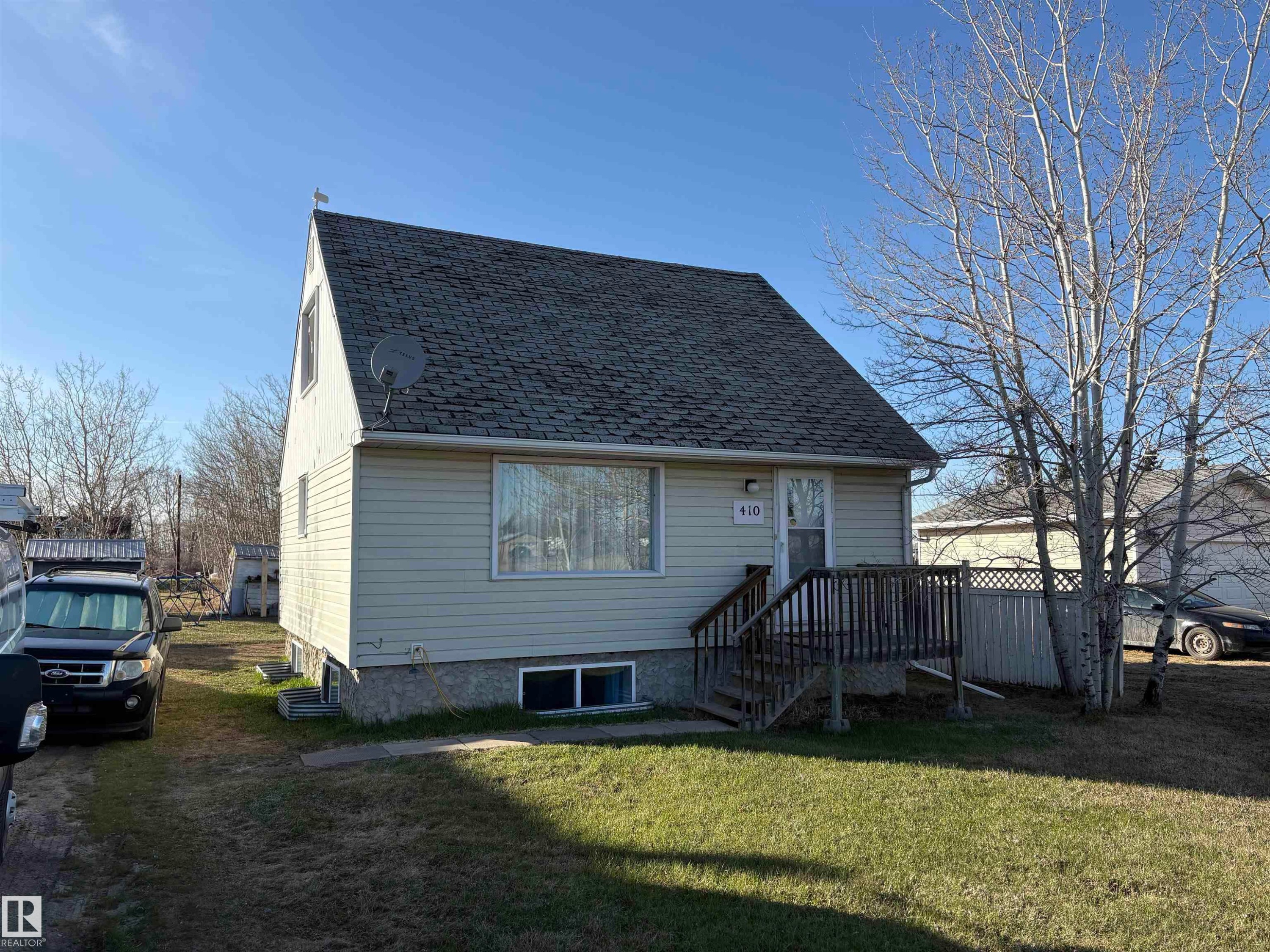 Front exterior with light-colored siding and a dark shingle roof - 410 Main St, Alcomdale, AB - Outdoor