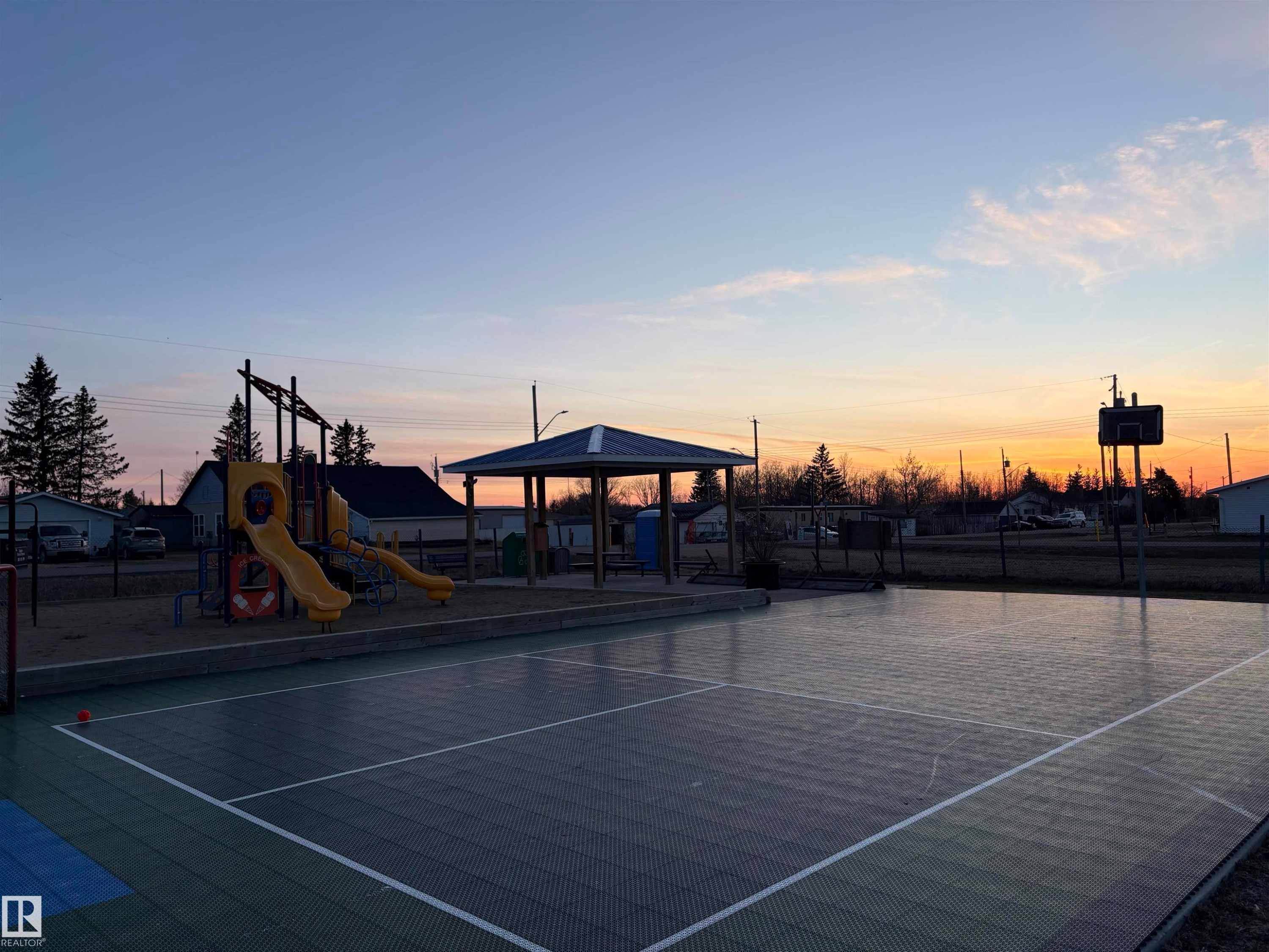 Recreational multi-sport court with visible boundary lines, surrounded by a chain-link fence - 410 Main St, Alcomdale, AB - Outdoor With View