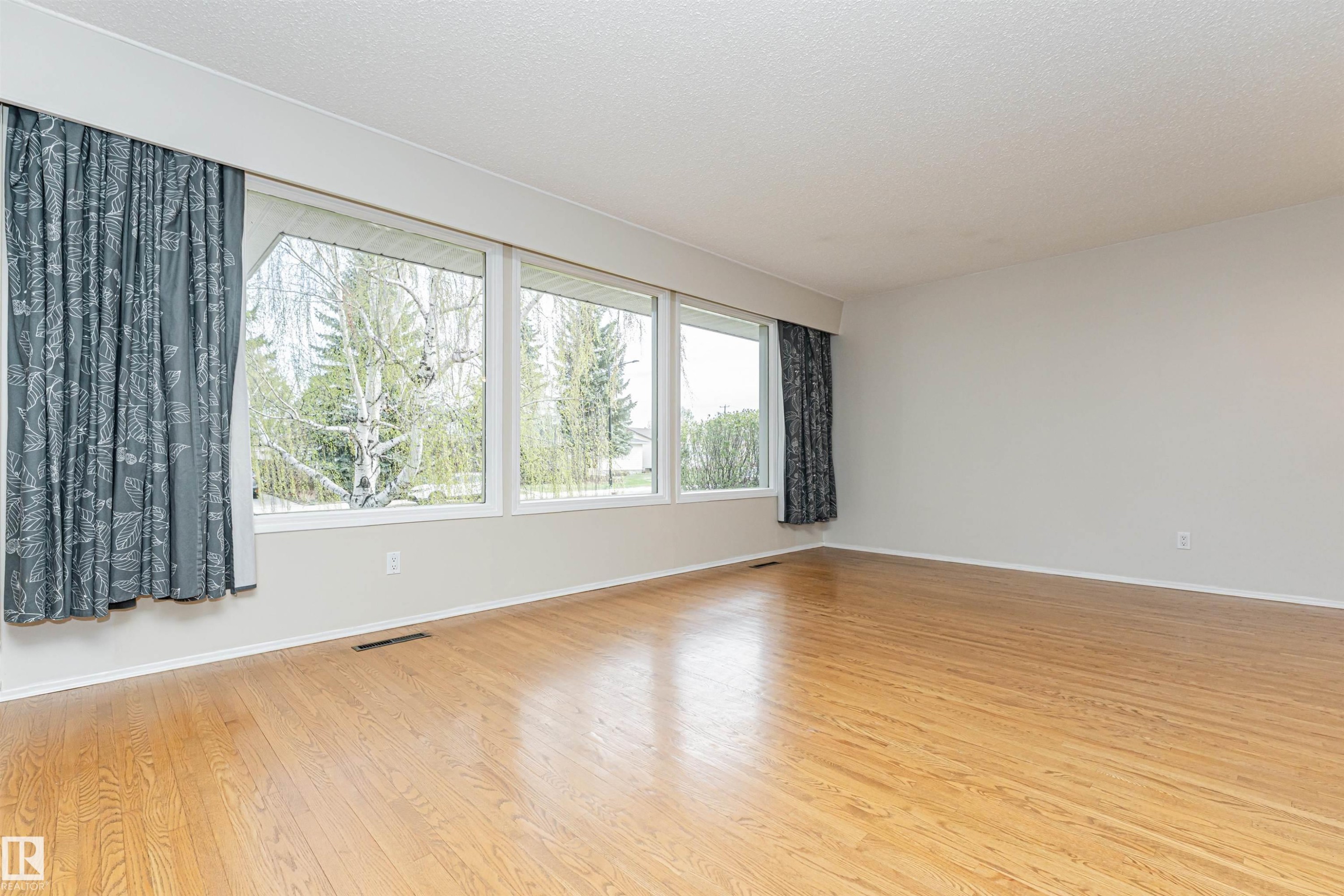 Room featuring wood-finish flooring, a neutral color palette, and multiple large windows - 11423 50 Avenue, Edmonton, AB - Indoor Photo Showing Other Room