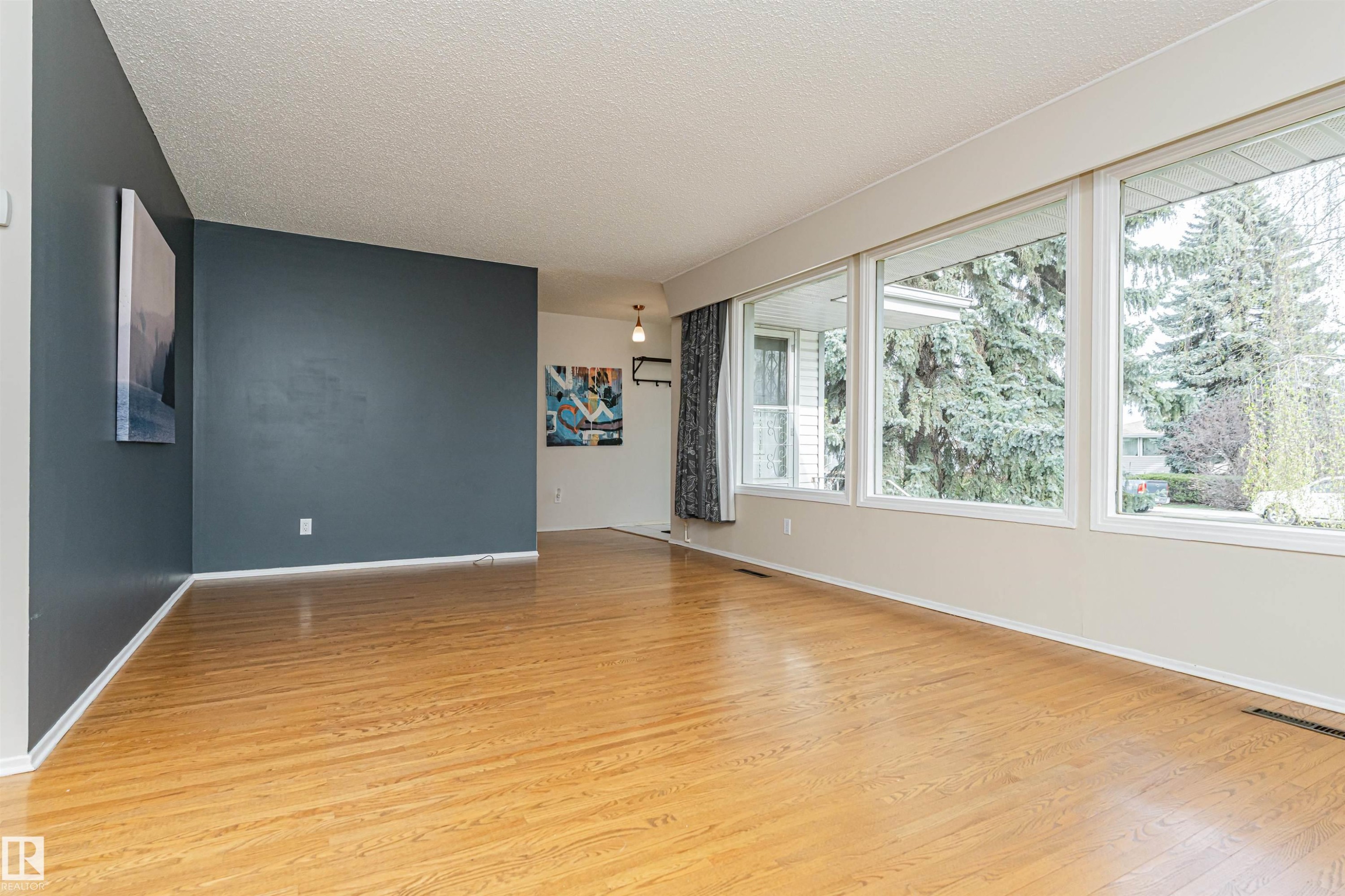 Room featuring expansive windows, wood-finish flooring, and a contrasting accent wall - 11423 50 Avenue, Edmonton, AB - Indoor Photo Showing Other Room