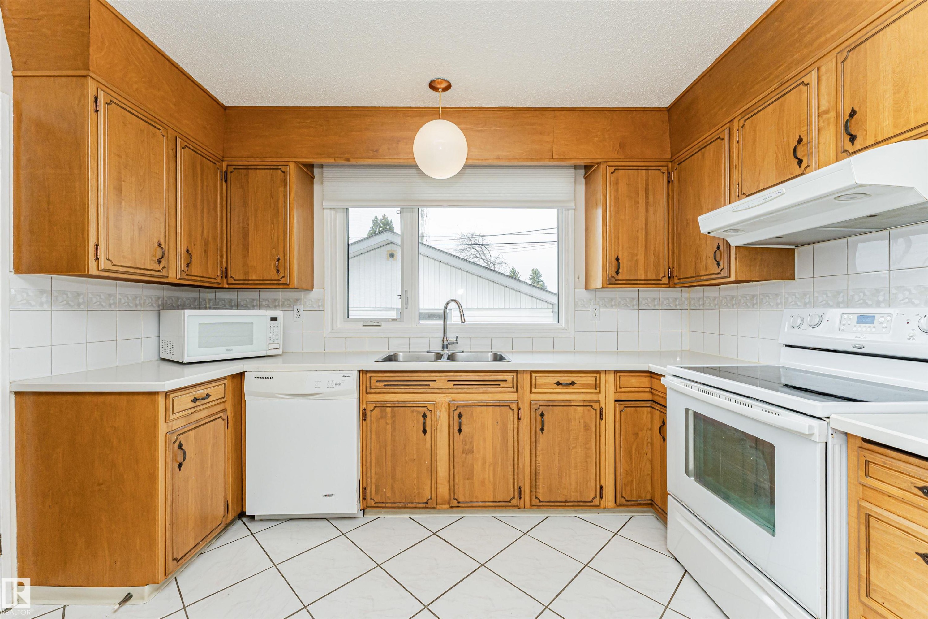 Kitchen featuring extensive wood cabinetry, white tile flooring, white countertops, and white tile backsplash - 11423 50 Avenue, Edmonton, AB - Indoor Photo Showing Kitchen With Double Sink