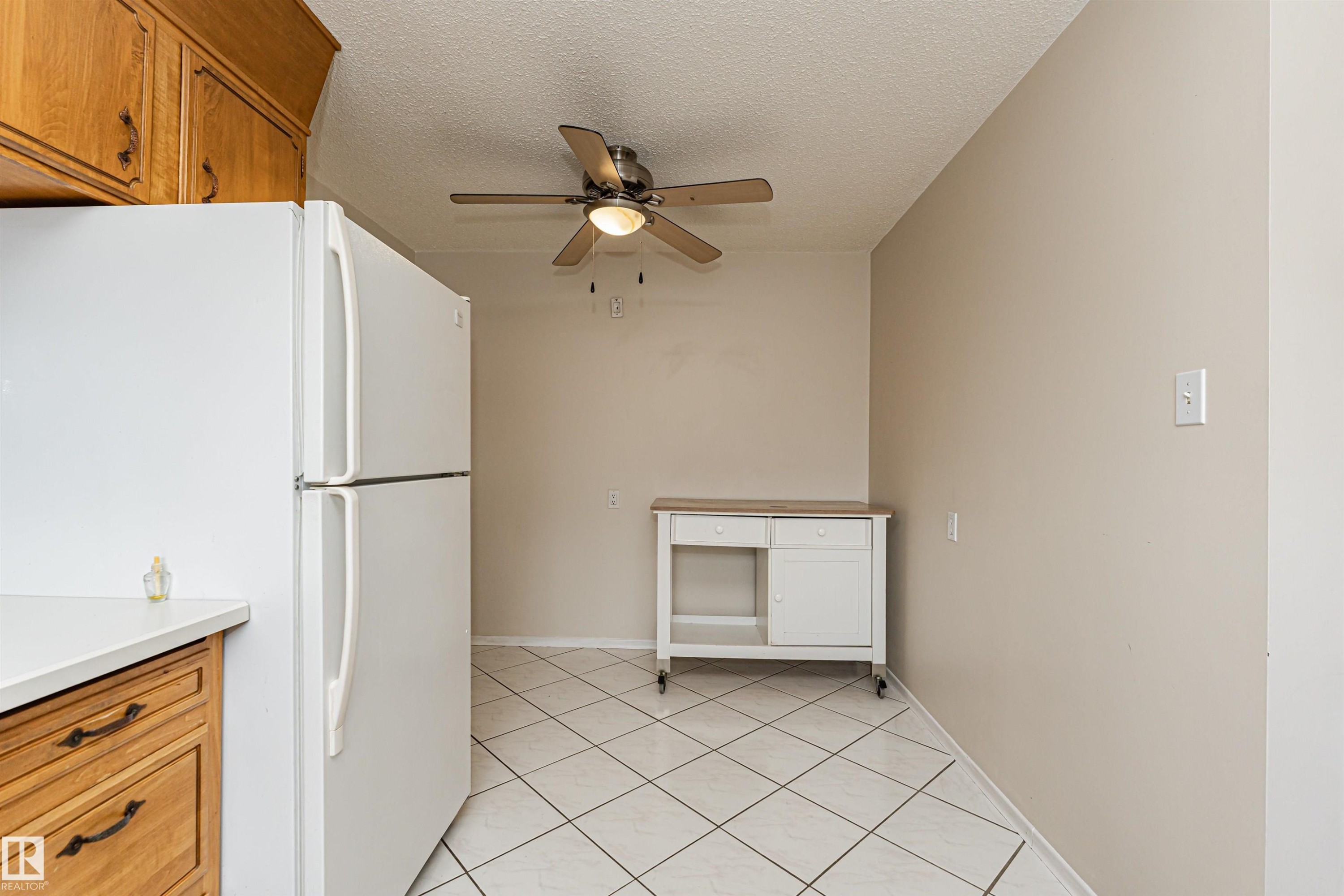 Kitchen area featuring wood cabinetry, white countertops, and diagonal white tile flooring - 11423 50 Avenue, Edmonton, AB - Indoor