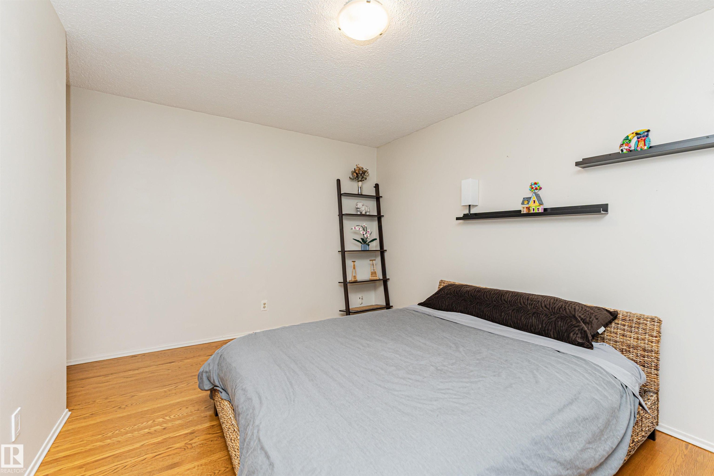 Bedroom featuring wood-finish flooring, a textured ceiling, and a flush-mount ceiling light - 11423 50 Avenue, Edmonton, AB - Indoor Photo Showing Bedroom