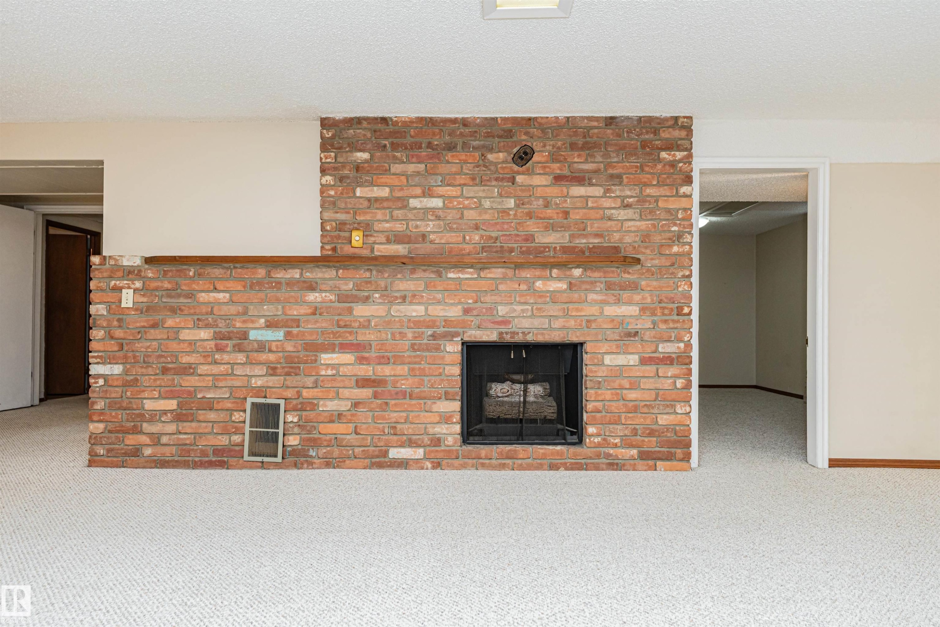 Brick fireplace featuring a black metal firebox and a wooden mantel - 11423 50 Avenue, Edmonton, AB - Indoor Photo Showing Living Room With Fireplace