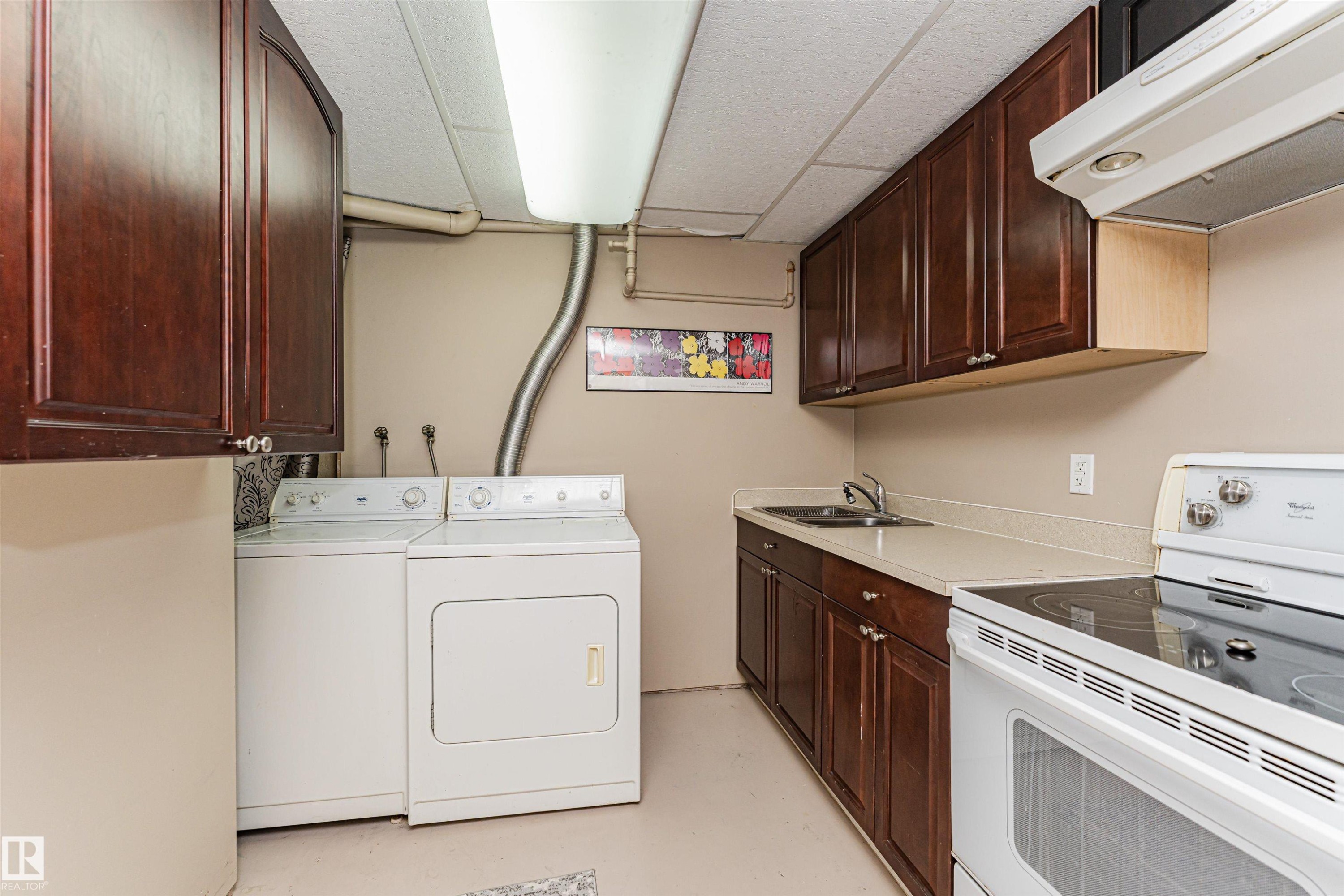 Utility area featuring dark wood-finish cabinetry, a double basin sink, and a white electric range - 11423 50 Avenue, Edmonton, AB - Indoor Photo Showing Laundry Room