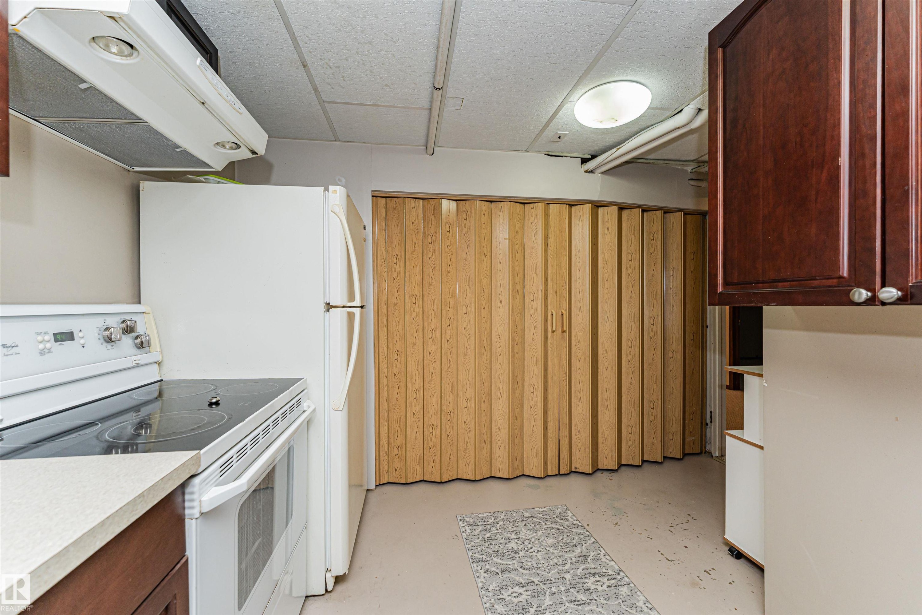 Compact kitchen space featuring a white electric range with a built-in oven, a white refrigerator, and light-toned countertops - 11423 50 Avenue, Edmonton, AB - Indoor Photo Showing Kitchen