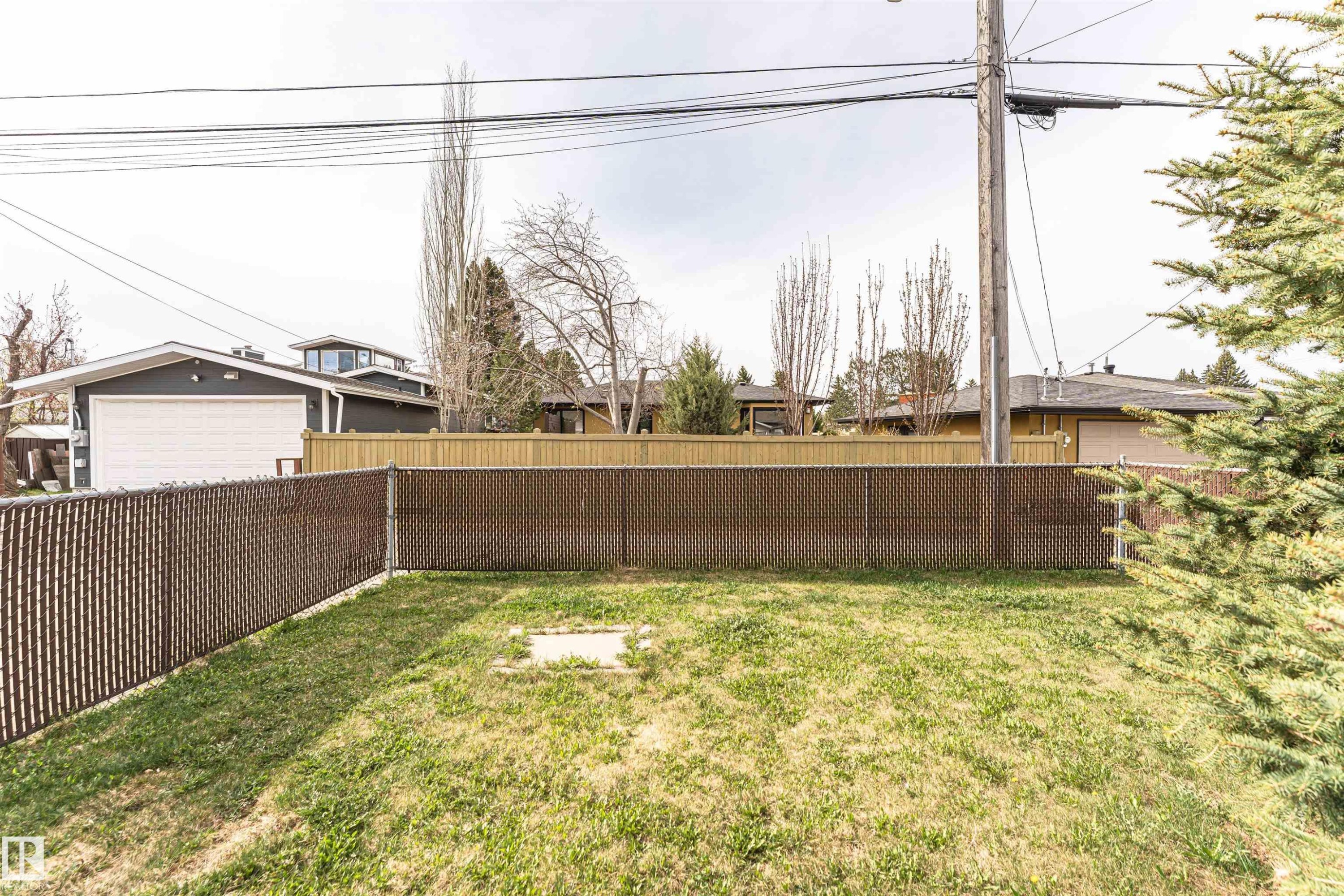 Expansive grassy yard area defined by chain-link fencing with privacy screening - 11423 50 Avenue, Edmonton, AB - Outdoor