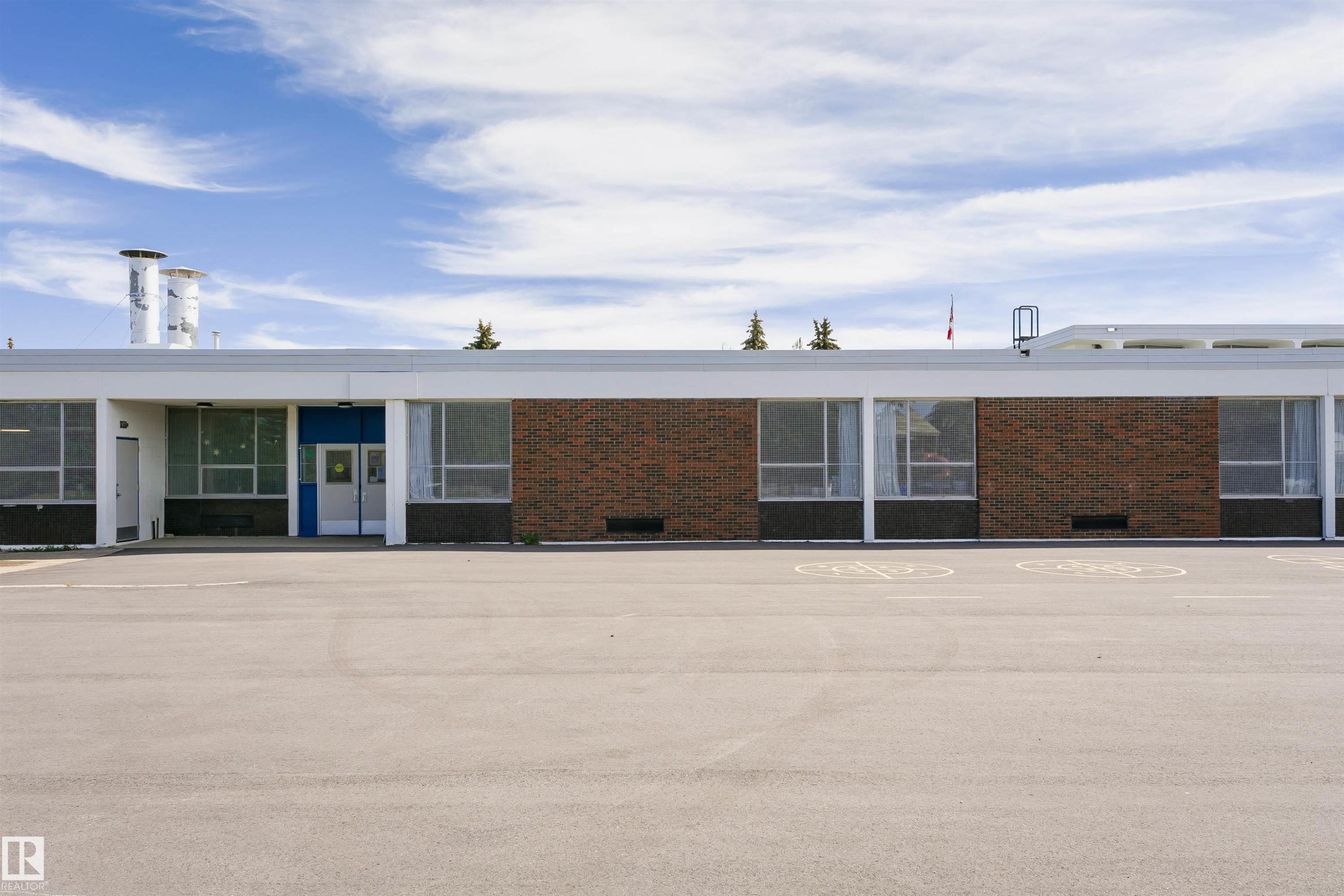Expansive paved lot fronting a single-story building with a flat roofline - 11423 50 Avenue, Edmonton, AB - Outdoor