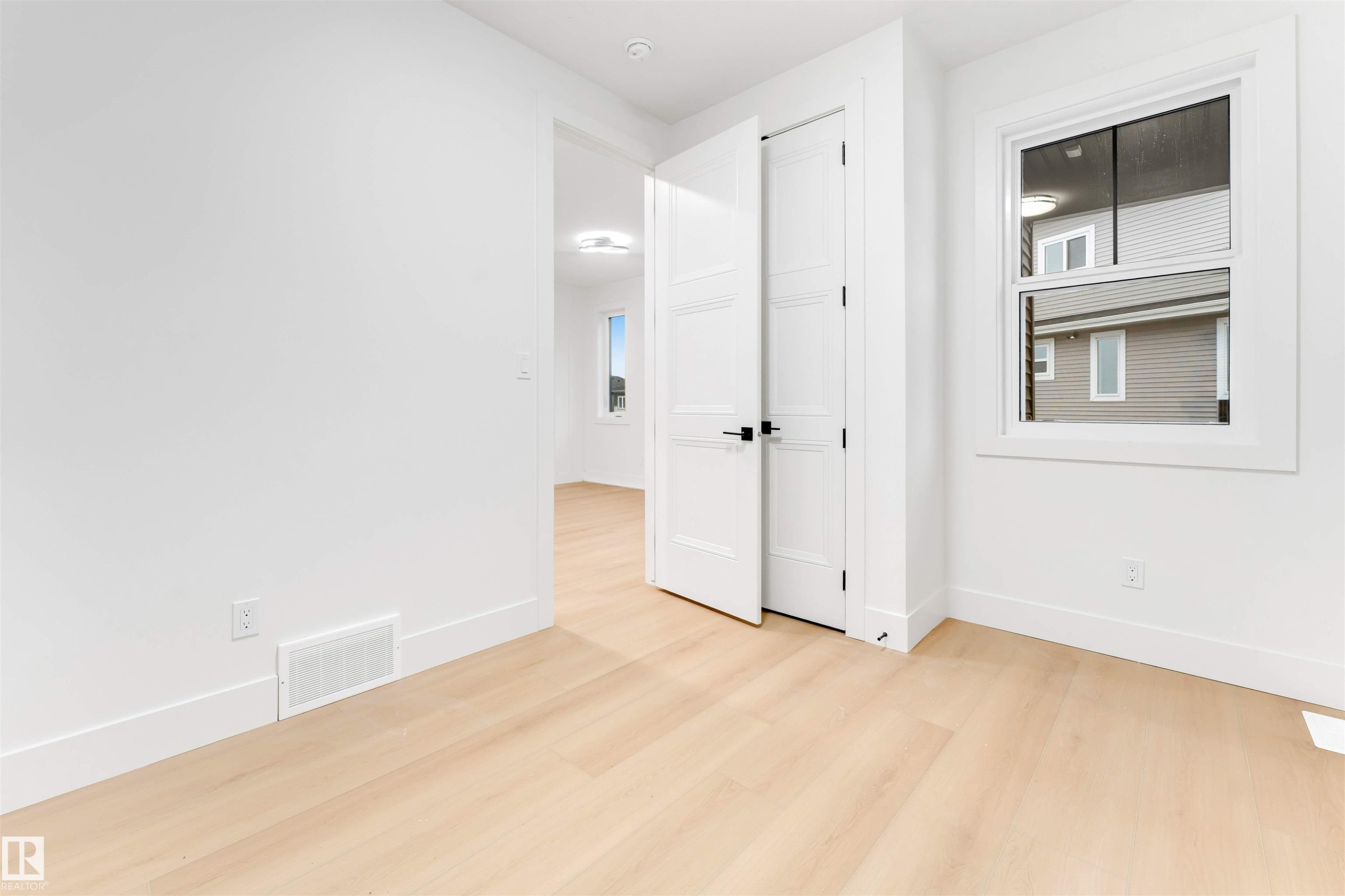 The room features light-toned hardwood flooring, white walls, and a window with white trim - 4004 35 Street, Beaumont, AB - Indoor Photo Showing Other Room