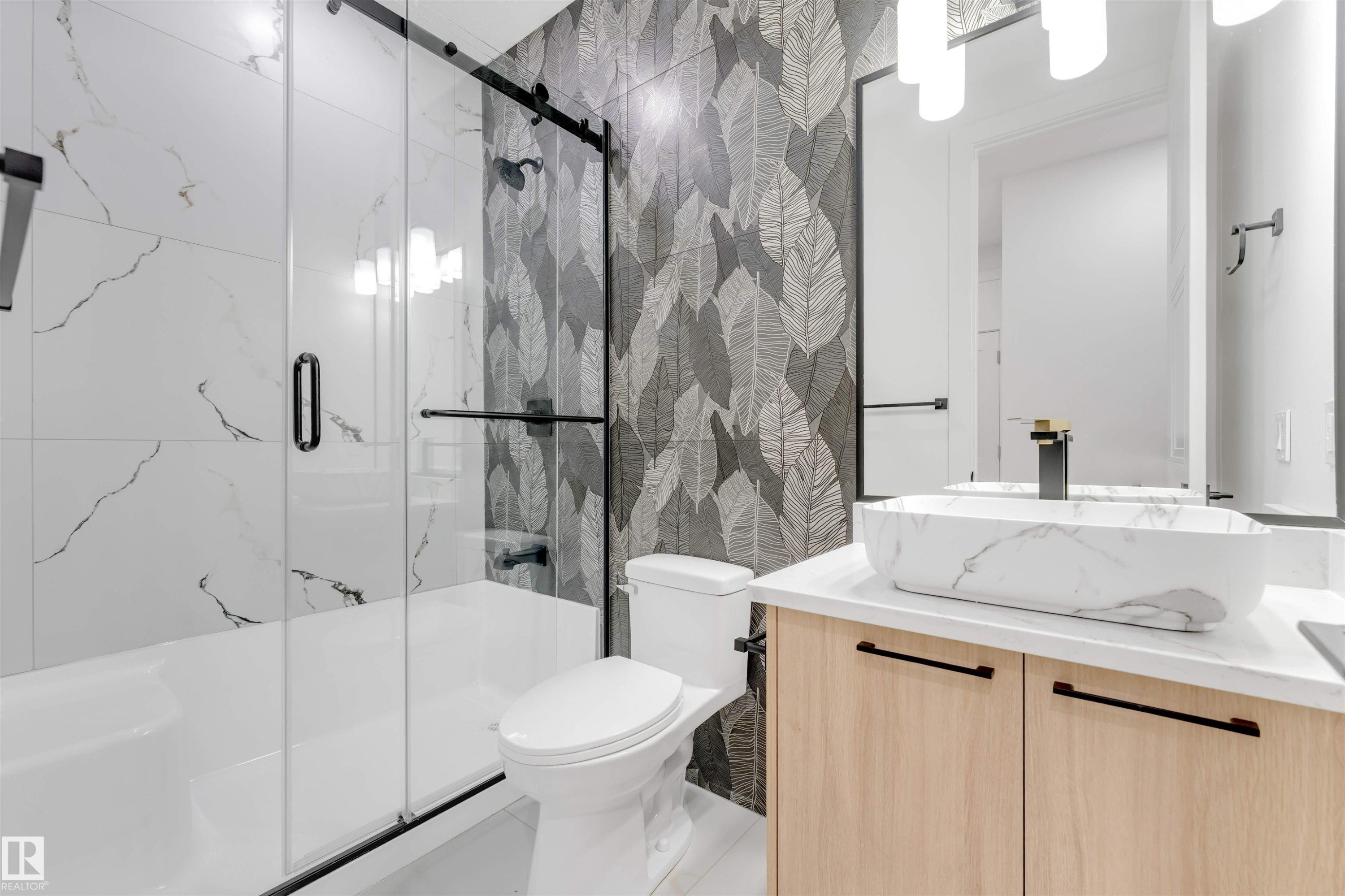 The bathroom features a modern vanity with a vessel sink, a shower with a sliding glass door, and stylish patterned wall tiles - 4004 35 Street, Beaumont, AB - Indoor Photo Showing Bathroom