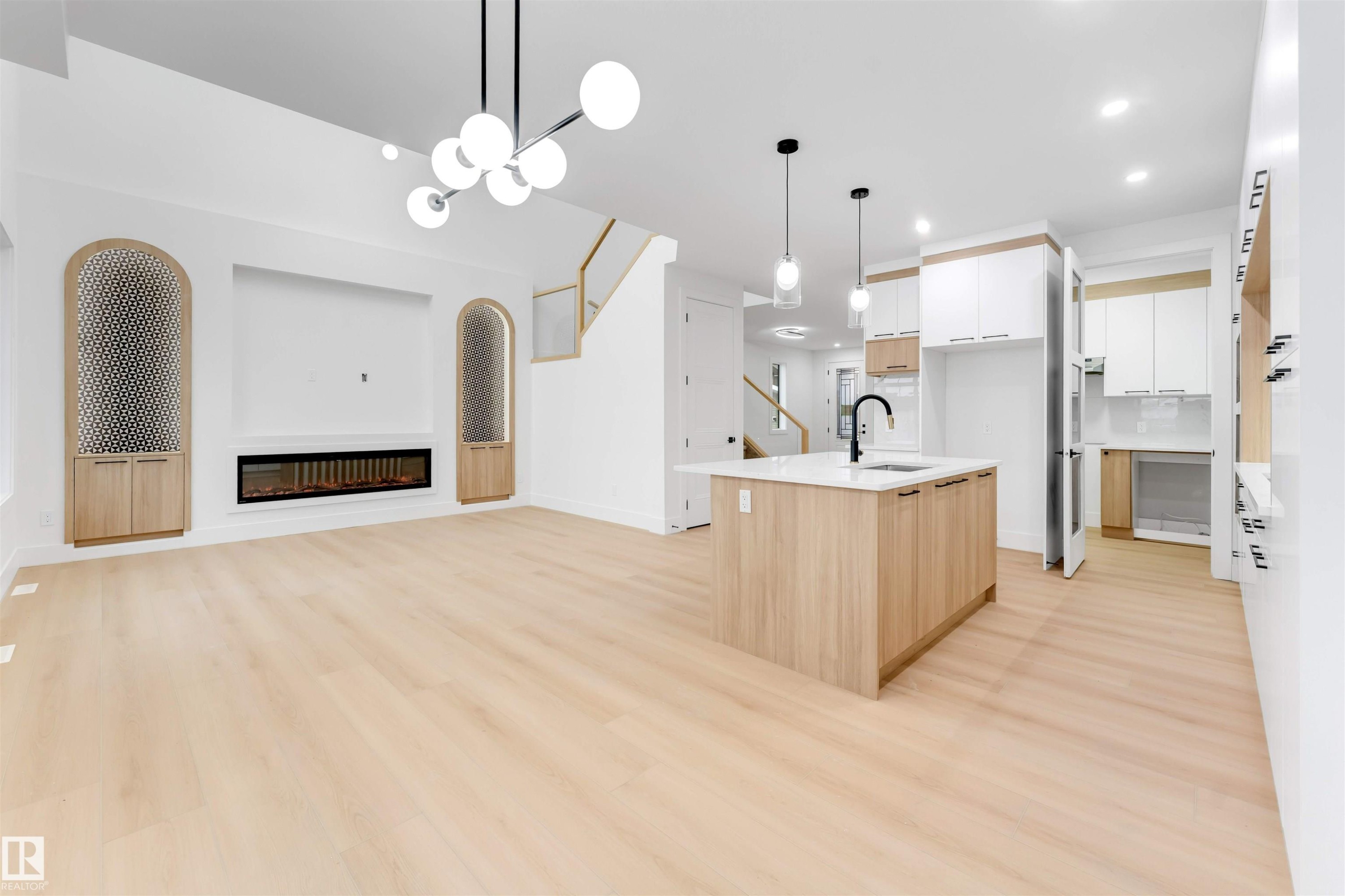 Open-concept living area with light-toned flooring, a modern linear fireplace, and custom built-in cabinetry - 4004 35 Street, Beaumont, AB - Indoor Photo Showing Other Room