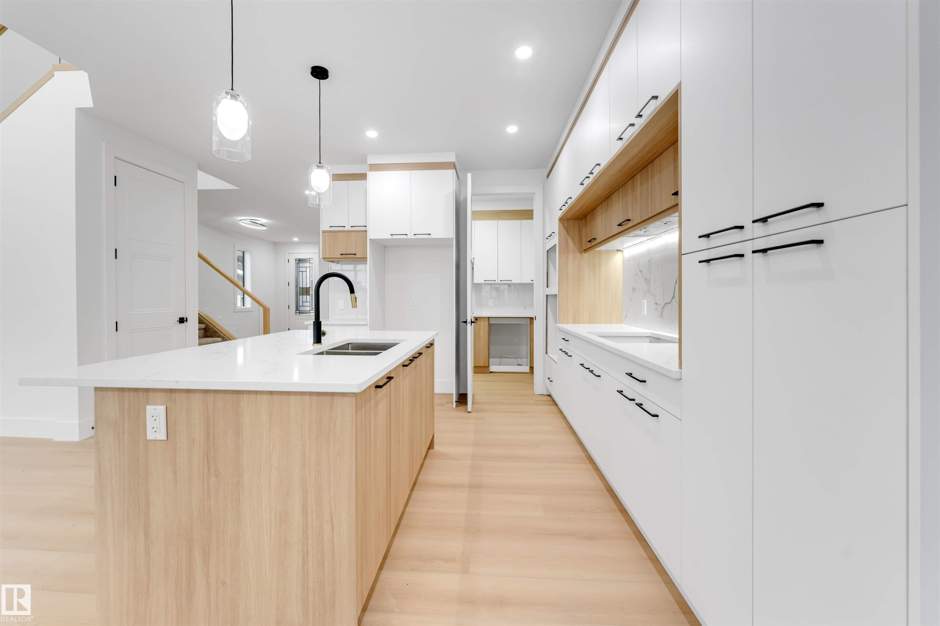 Modern kitchen featuring a central island with a sink and a black faucet, complemented by light wood cabinetry - 4004 35 Street, Beaumont, AB - Indoor Photo Showing Kitchen With Double Sink With Upgraded Kitchen