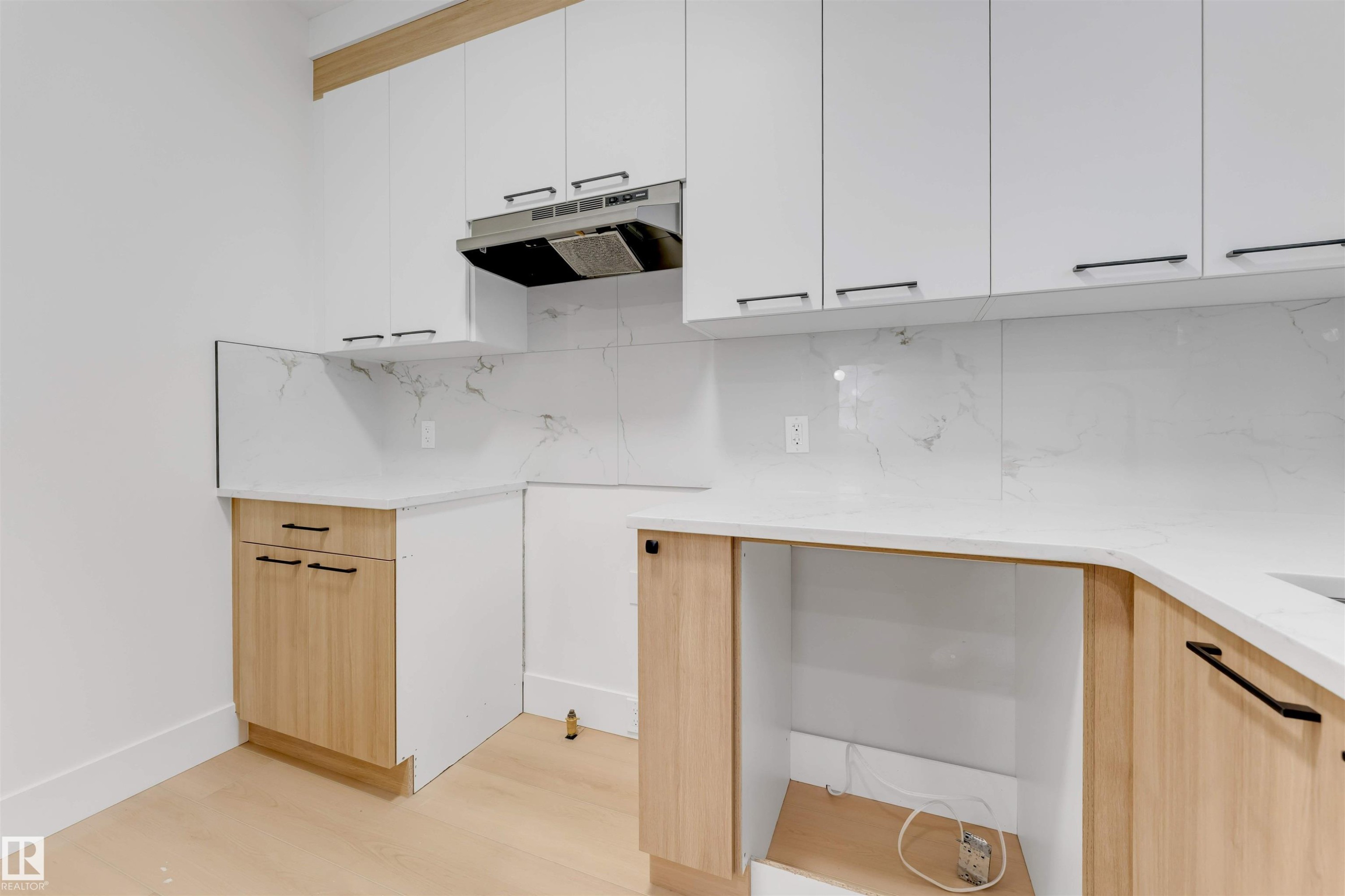 The kitchen features white upper cabinetry, wood-toned lower cabinetry, and white countertops - 4004 35 Street, Beaumont, AB - Indoor Photo Showing Kitchen