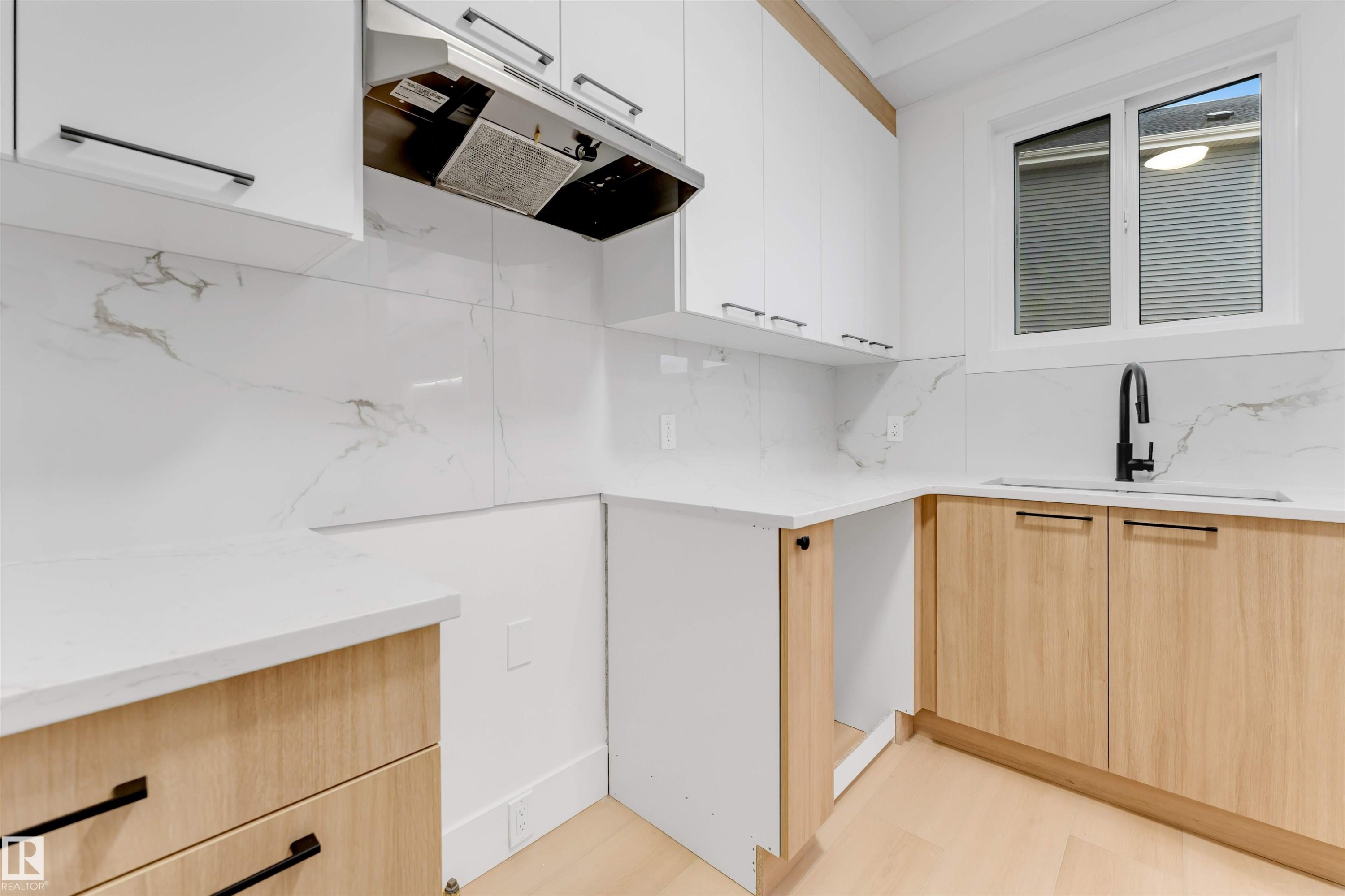 This kitchen features white upper cabinetry, light wood lower cabinetry, and white countertops - 4004 35 Street, Beaumont, AB - Indoor