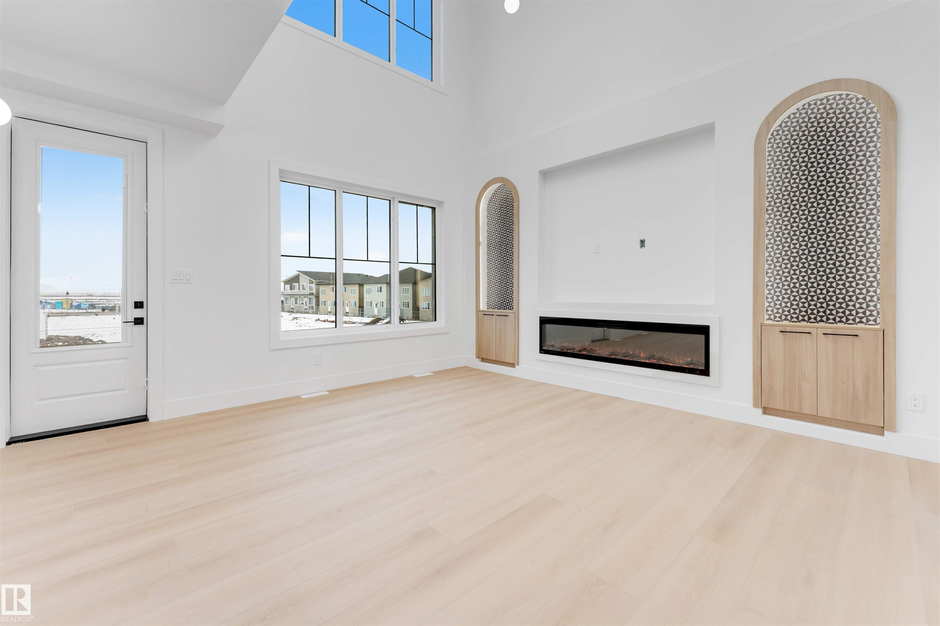 Living area featuring light-colored flooring, a large window, and an electric fireplace - 4004 35 Street, Beaumont, AB - Indoor With Fireplace
